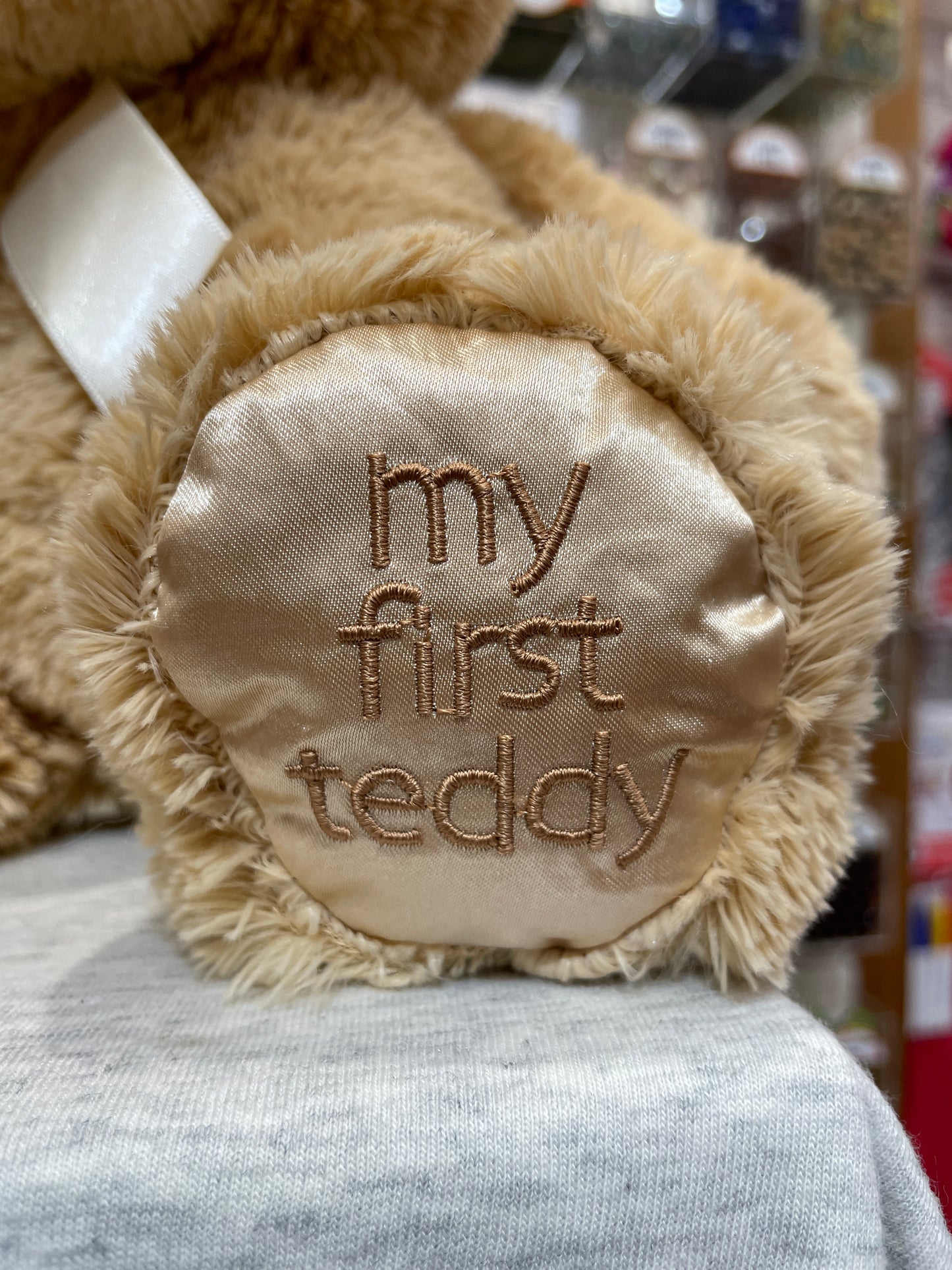 Soft tan teddy bear foot with "My First Teddy" embroidered on satin pad, perfect for babies
