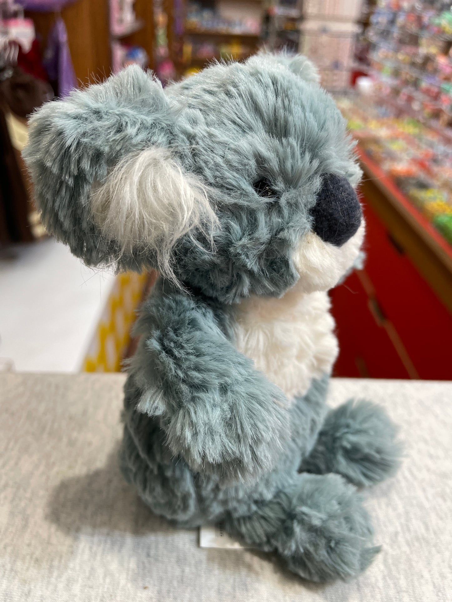 Soft, cuddly Mary Meyer Puttling Koala plush toy with gray fur and white accents, sitting in a toy store display