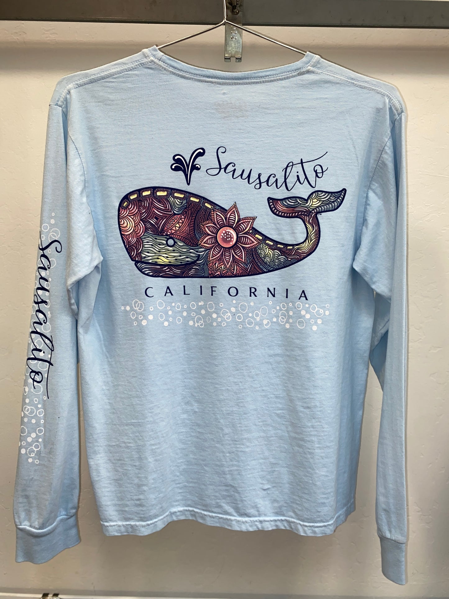 Sausalito California long sleeve t-shirt with colorful mandala whale design, bubbles, and floral patterns on light blue fabric