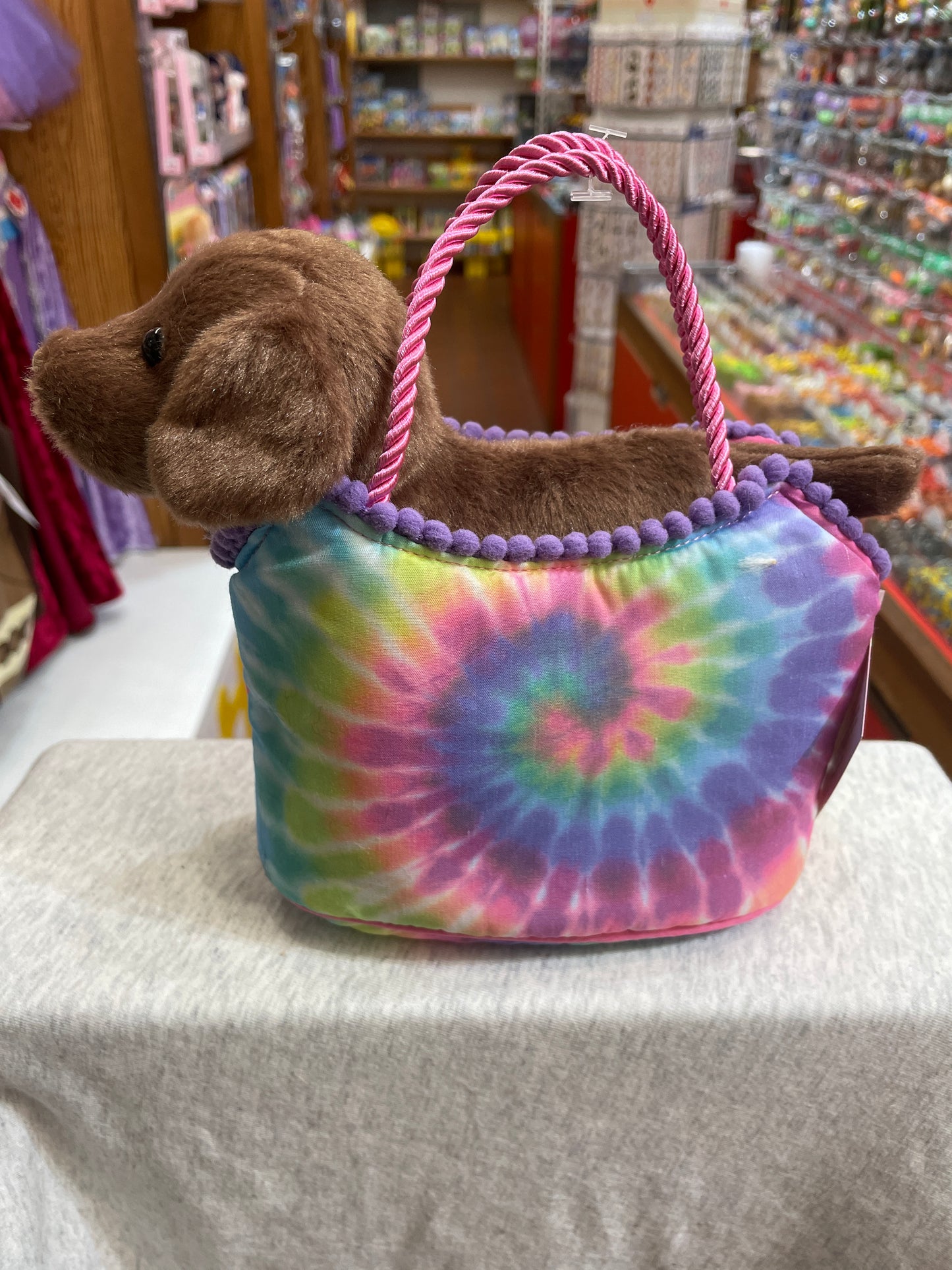 Tie-dye Sassy Pet Sak with plush Chocolate Lab puppy, colorful handbag for kids, displayed in toy store