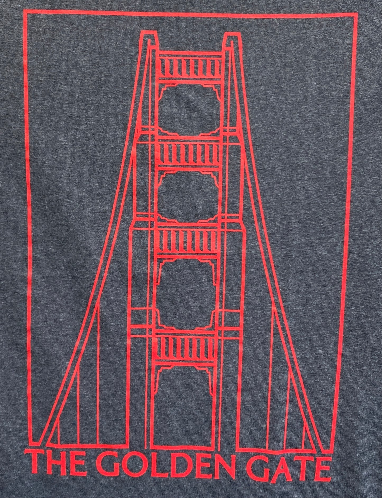 Red line drawing of Golden Gate Bridge tower on gray t-shirt, with "THE GOLDEN GATE" text underneath
