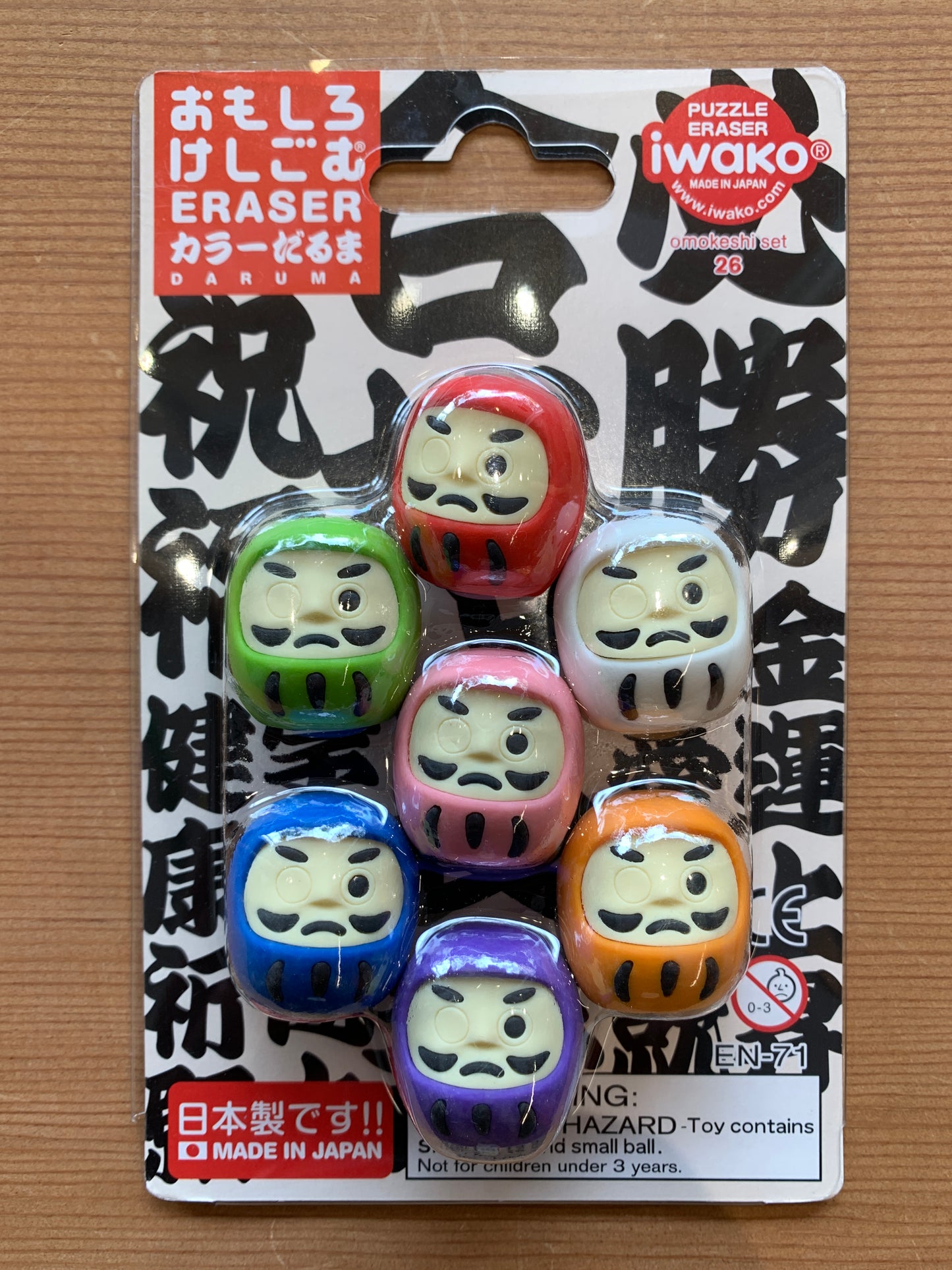 Colorful Daruma Japanese eraser set featuring 7 miniature dolls in various hues, packaged as Iwako puzzle erasers made in Japan