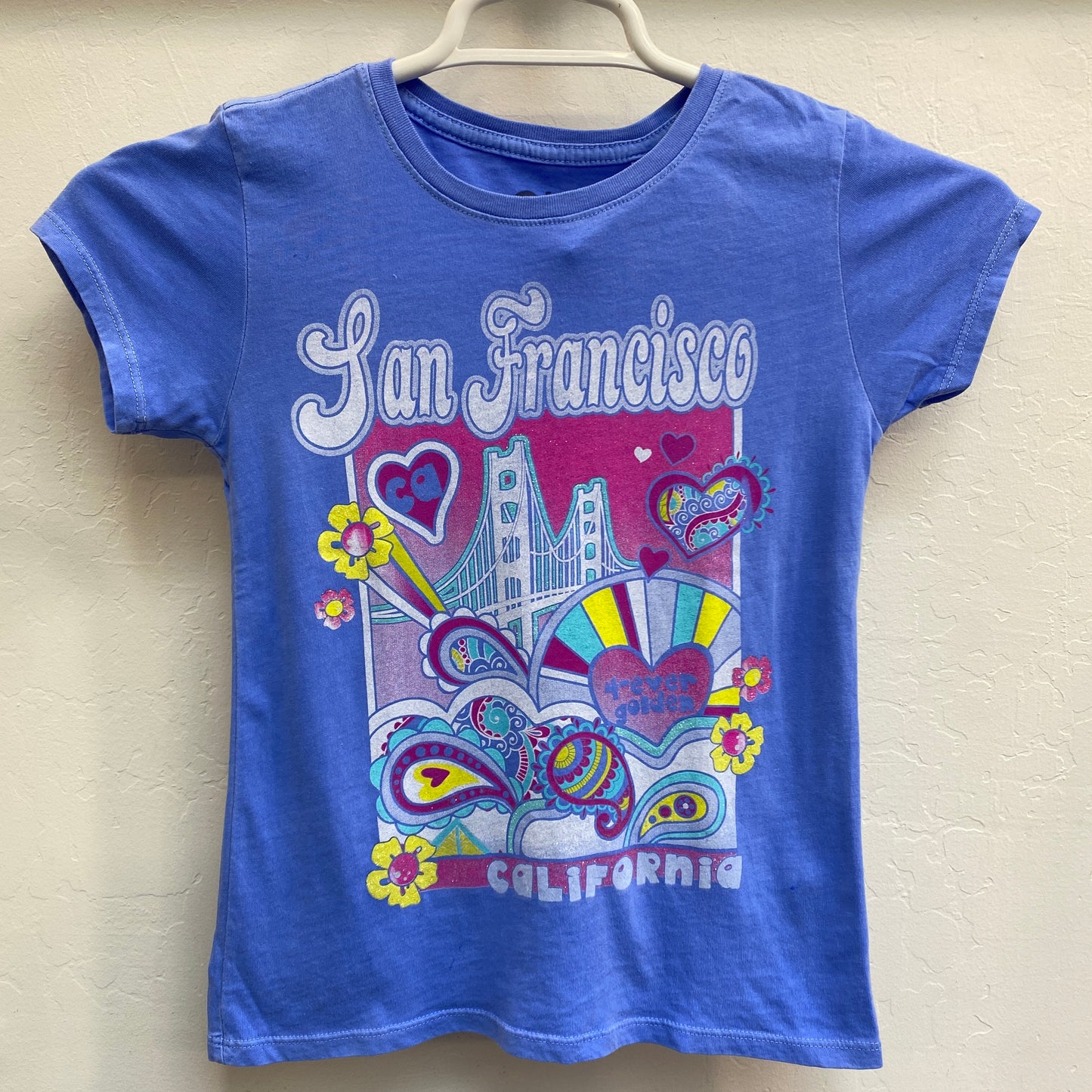 Girls' blue San Francisco t-shirt with colorful psychedelic design featuring Golden Gate Bridge, hearts, and flowers