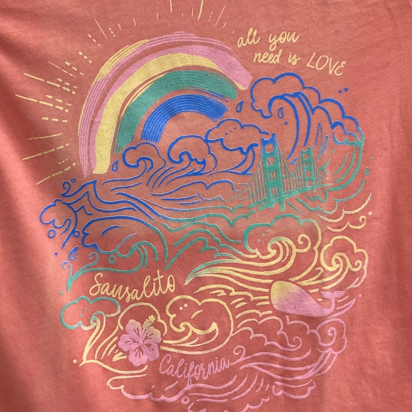 Colorful Sausalito t-shirt design with Golden Gate Bridge, rainbow, waves, whale, and "All you need is love" text on pink fabric