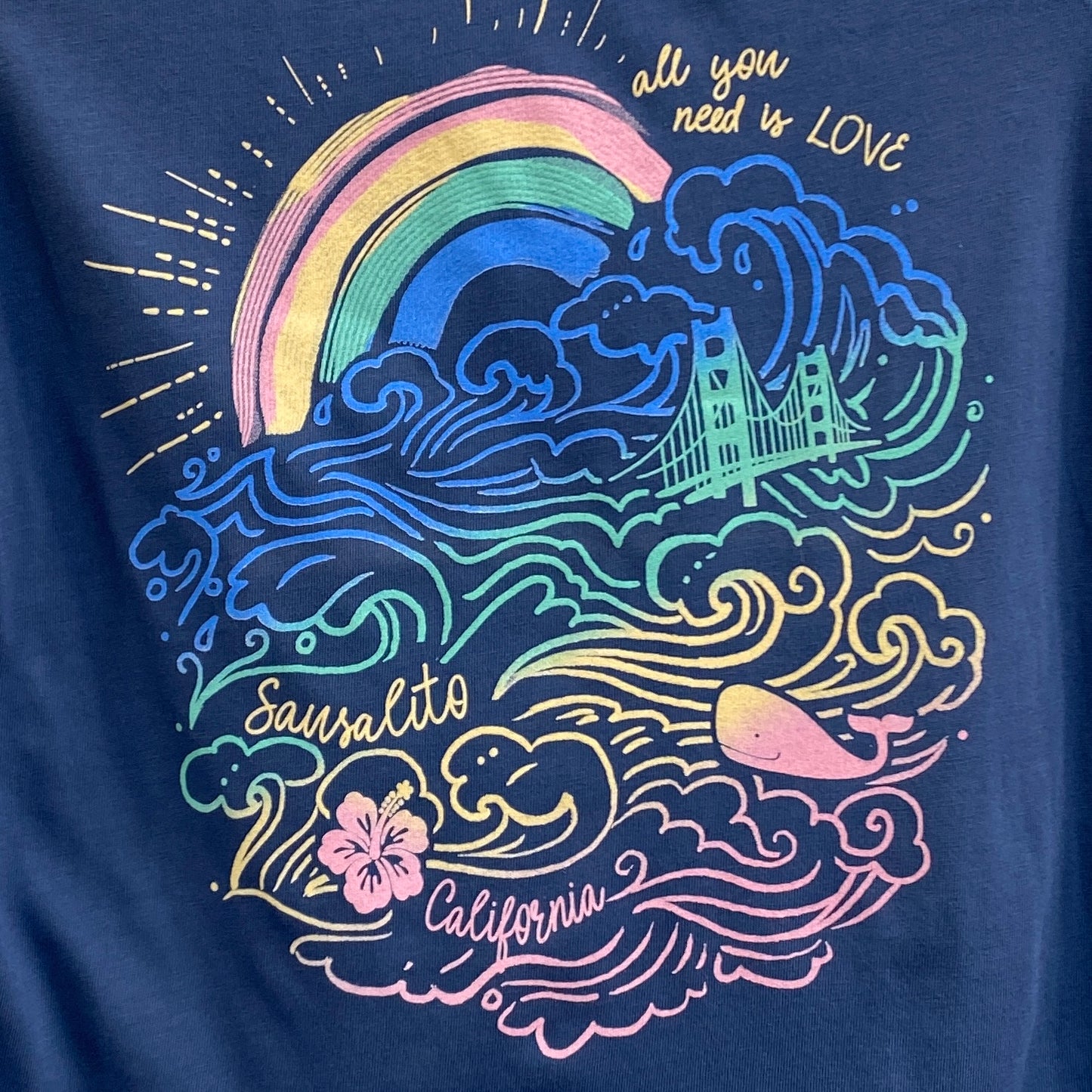 Colorful Sausalito t-shirt design with Golden Gate Bridge, rainbow, waves, whale, and flower on navy background