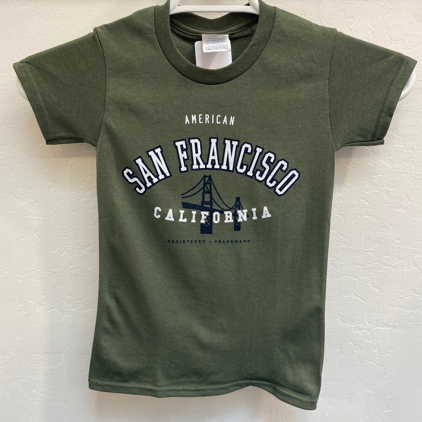 Green kids' t-shirt with "San Francisco California" and Golden Gate Bridge graphic, showcasing city's trademark design