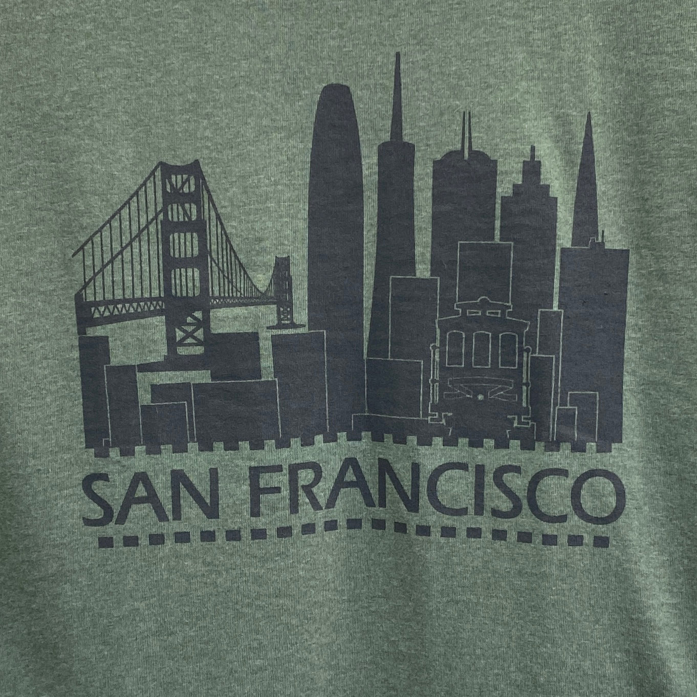 San Francisco retro skyline print on pine green t-shirt featuring Golden Gate Bridge, skyscrapers, and cable car silhouette