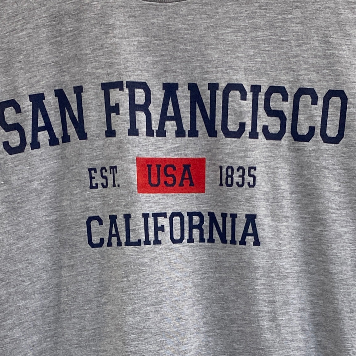 Gray cotton t-shirt with "San Francisco California USA Est. 1835" text in navy and red, showcasing city pride