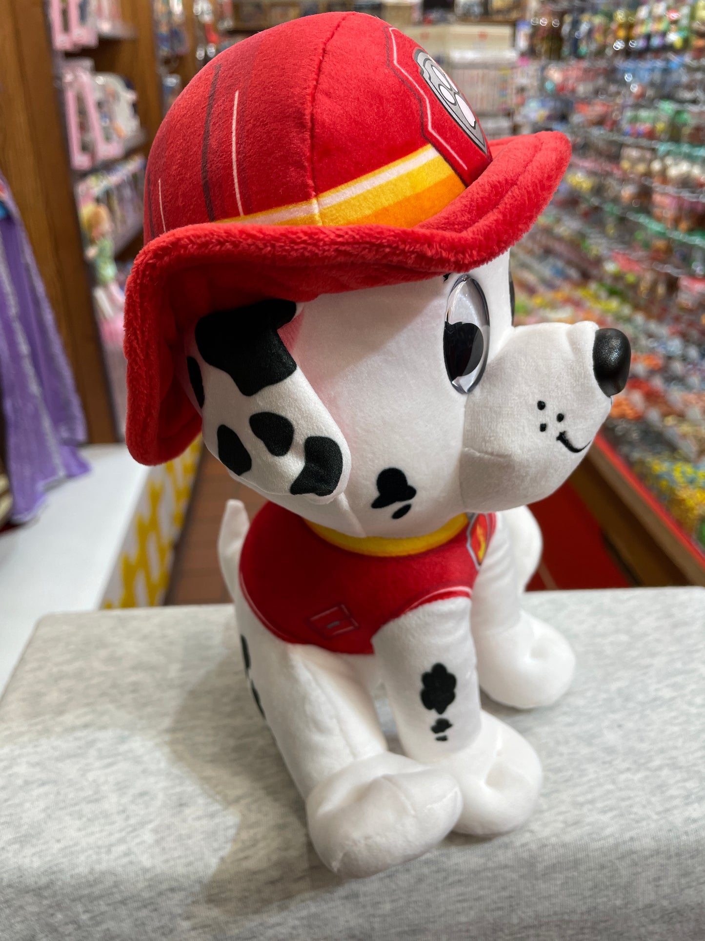 Gund Paw Patrol Marshall plush toy, featuring a smiling Dalmatian in red fireman uniform and hat, displayed in a store