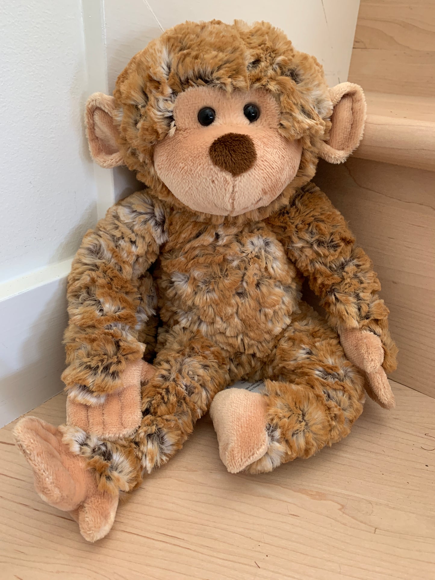 Soft, cuddly Douglas Bananas plush monkey toy, 18 inches tall, with fluffy brown fur and pink accents, sitting on wooden floor
