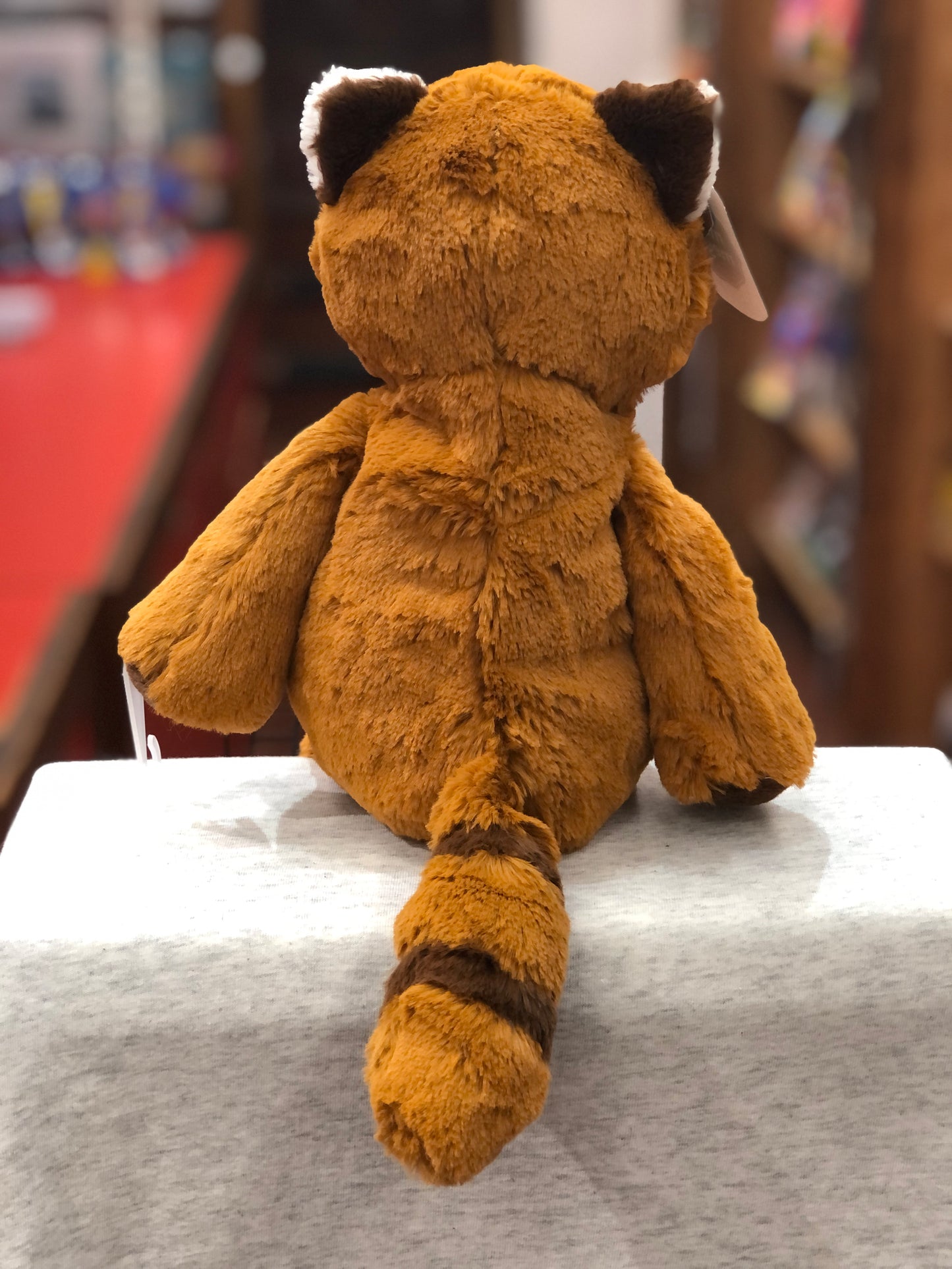 Soft, cuddly Mary Meyer Marshmallow Red Panda plush toy sitting on display, showing its fluffy back and tail