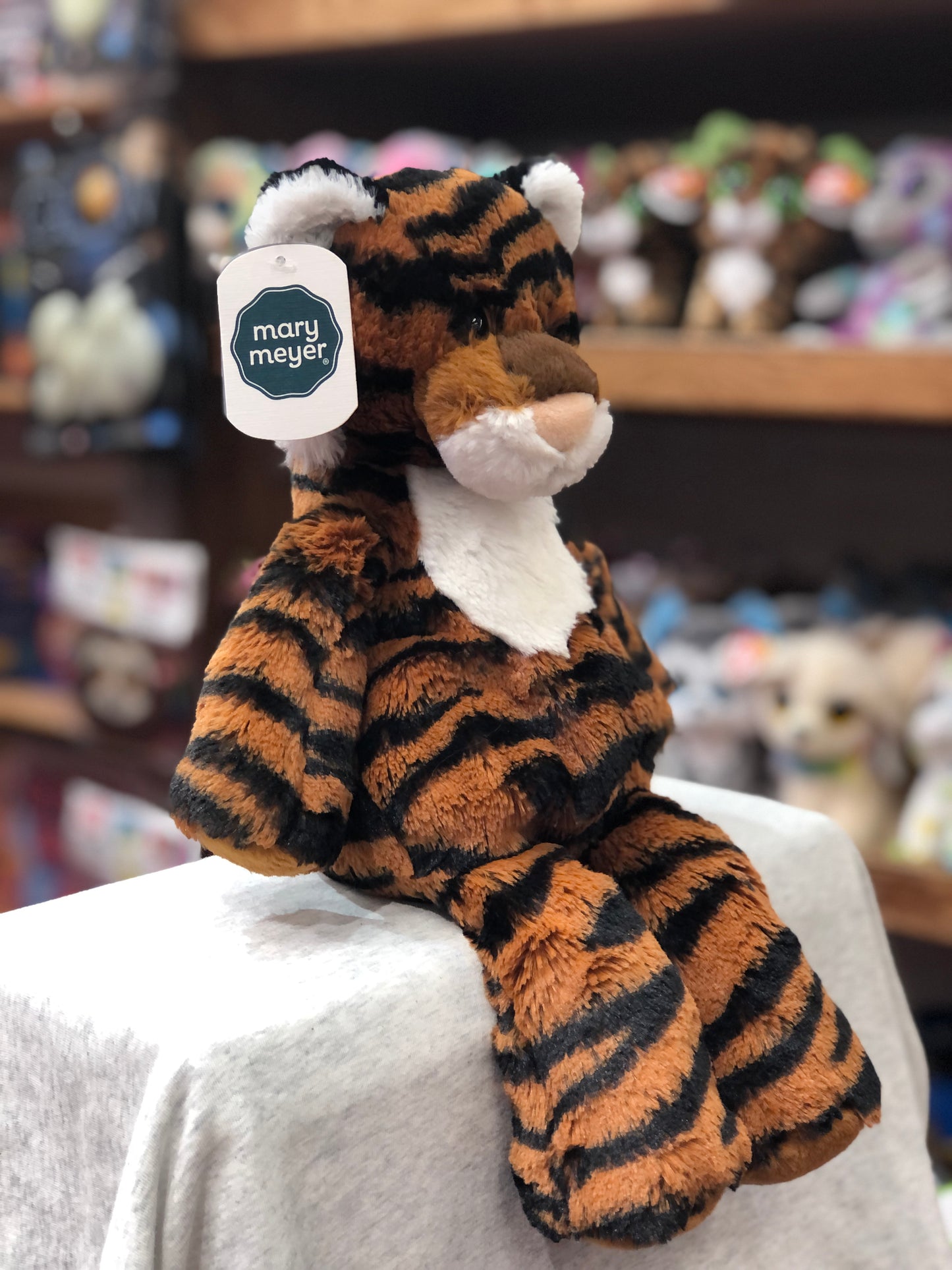 Mary Meyer Marshmallow Tiger plush toy, soft orange and black striped, sitting on display with brand tag attached