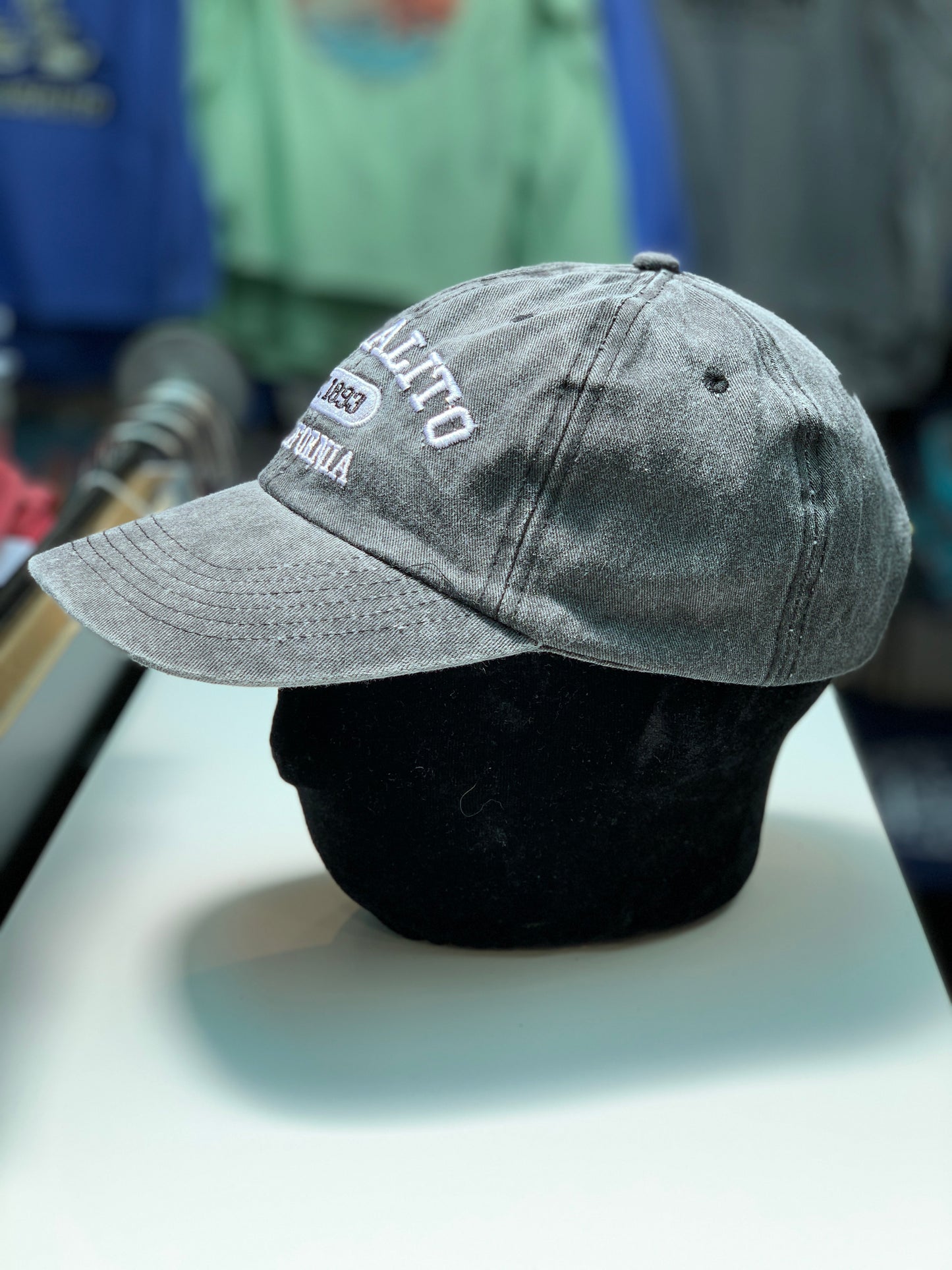 Distressed gray cotton baseball cap with "Sausalito Est. 1893" embroidery, displayed on stand