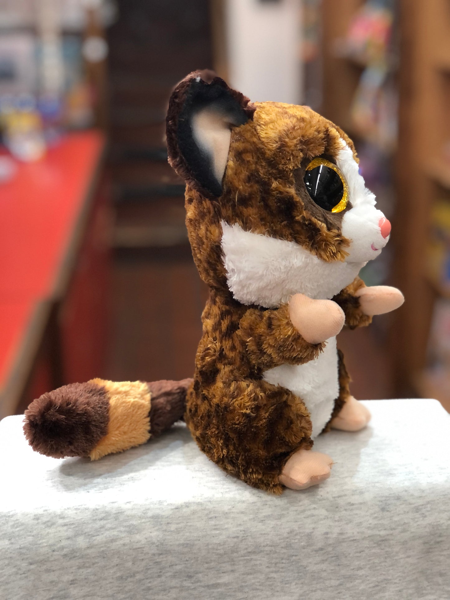 Ty Beanie Boo Binky brown bush baby plush with large eyes, white belly, and striped tail, sitting on display