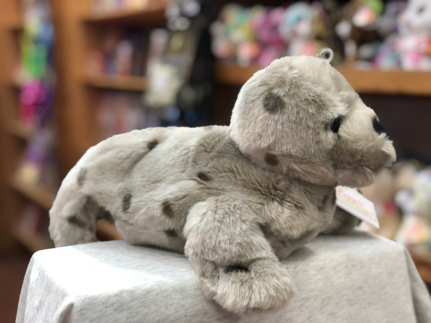 Cuddly grey seal full-bodied puppet by The Puppet Company, displayed on white surface in toy store setting