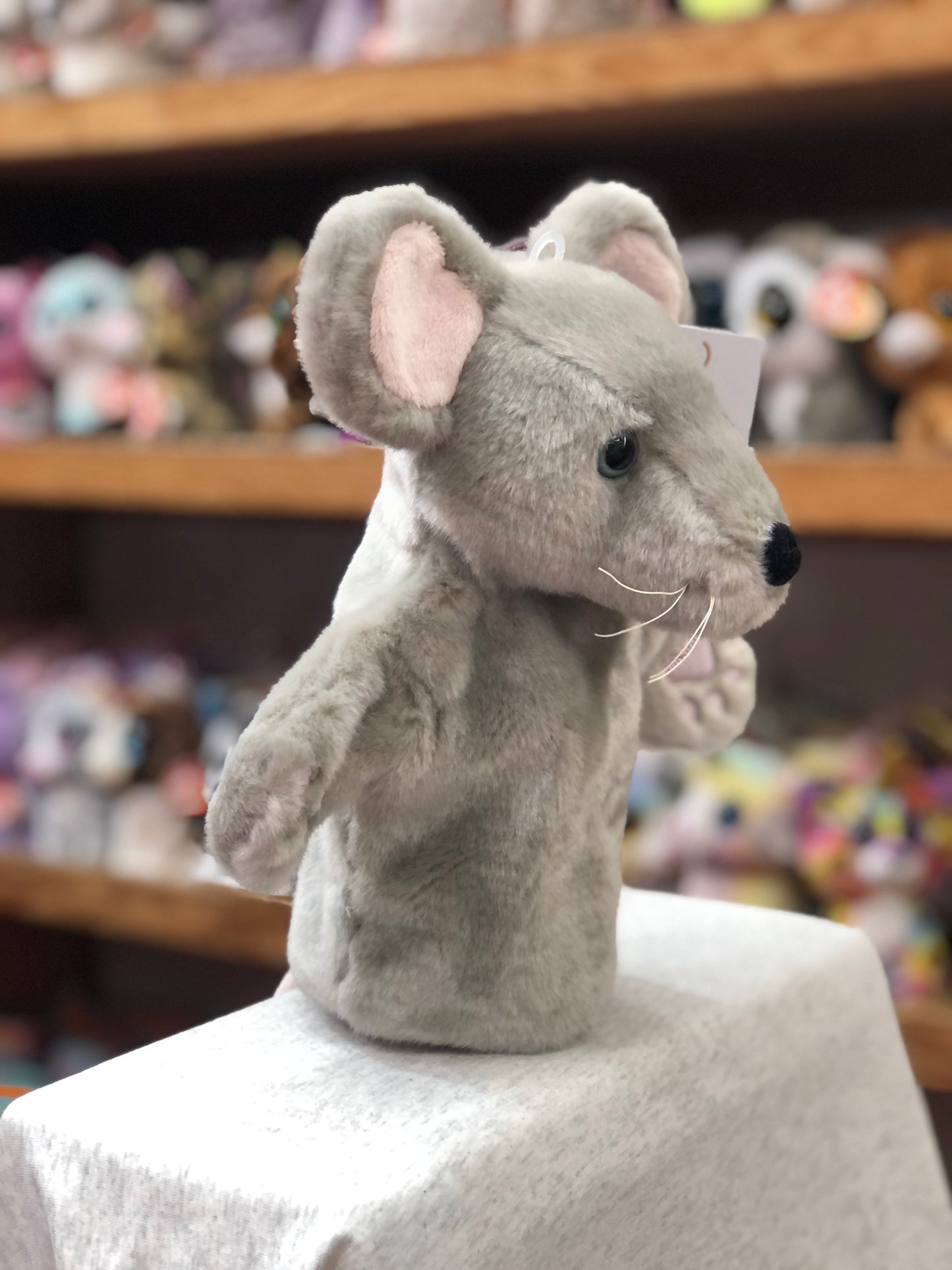 Plush grey mouse hand puppet from The Puppet Company's CarPets collection, displayed on shelf with other toys in background