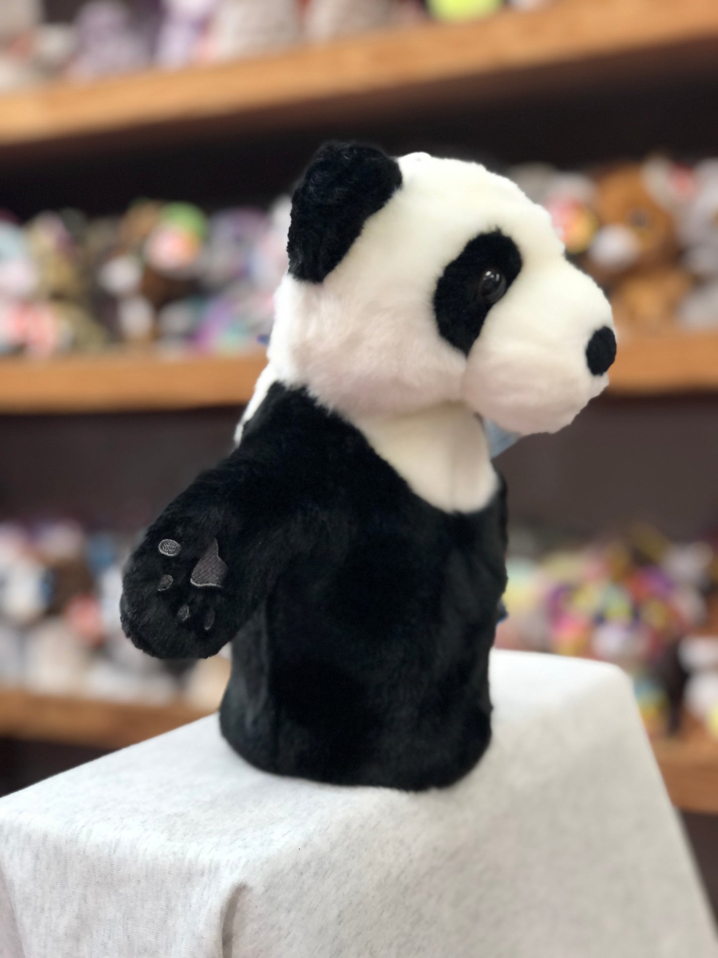 Plush panda hand puppet from The Puppet Company's CarPets collection, shown on display with other toys in background