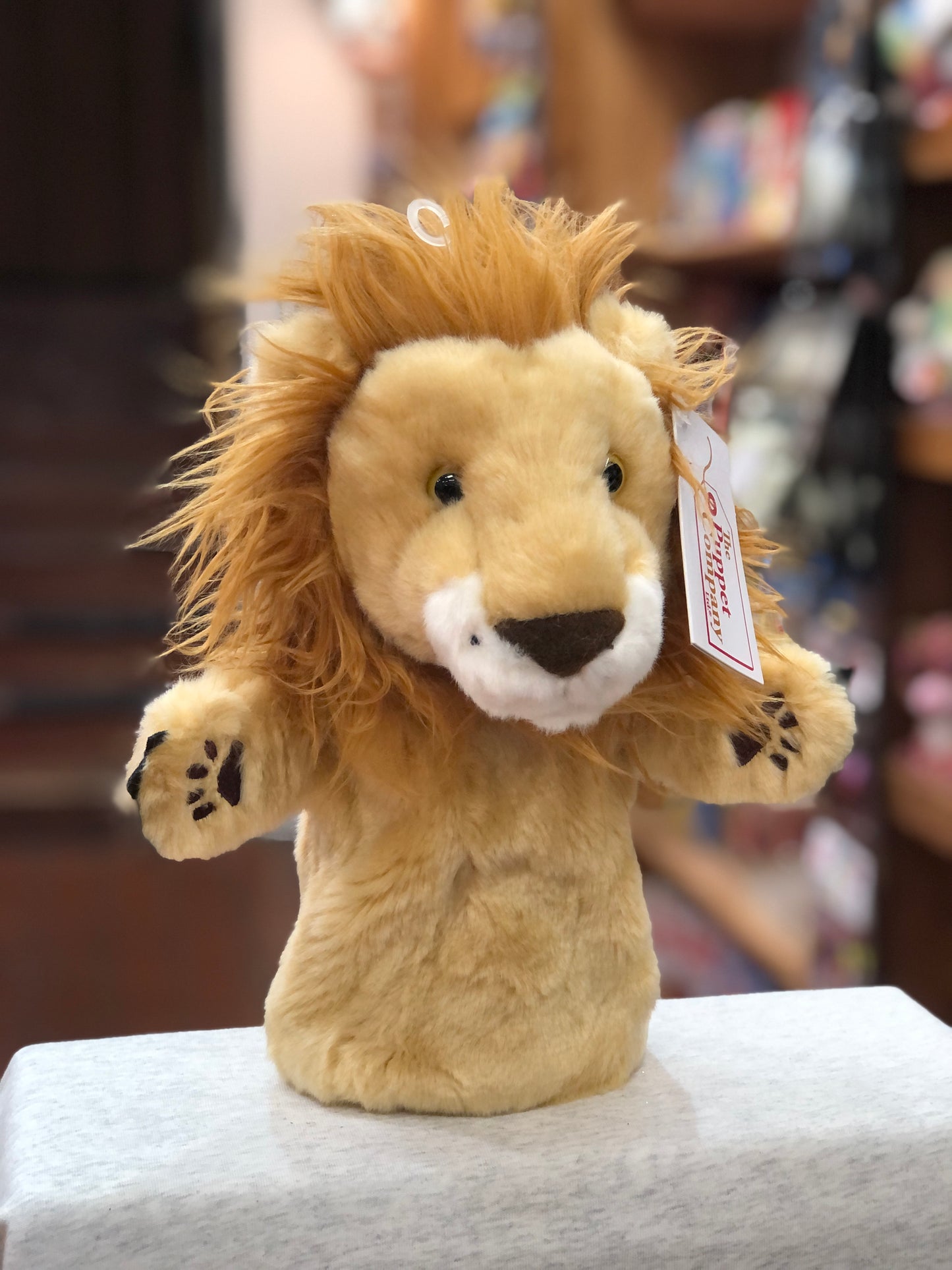 Plush lion hand puppet from The Puppet Company's CarPets collection, with fluffy mane and paw details, on display