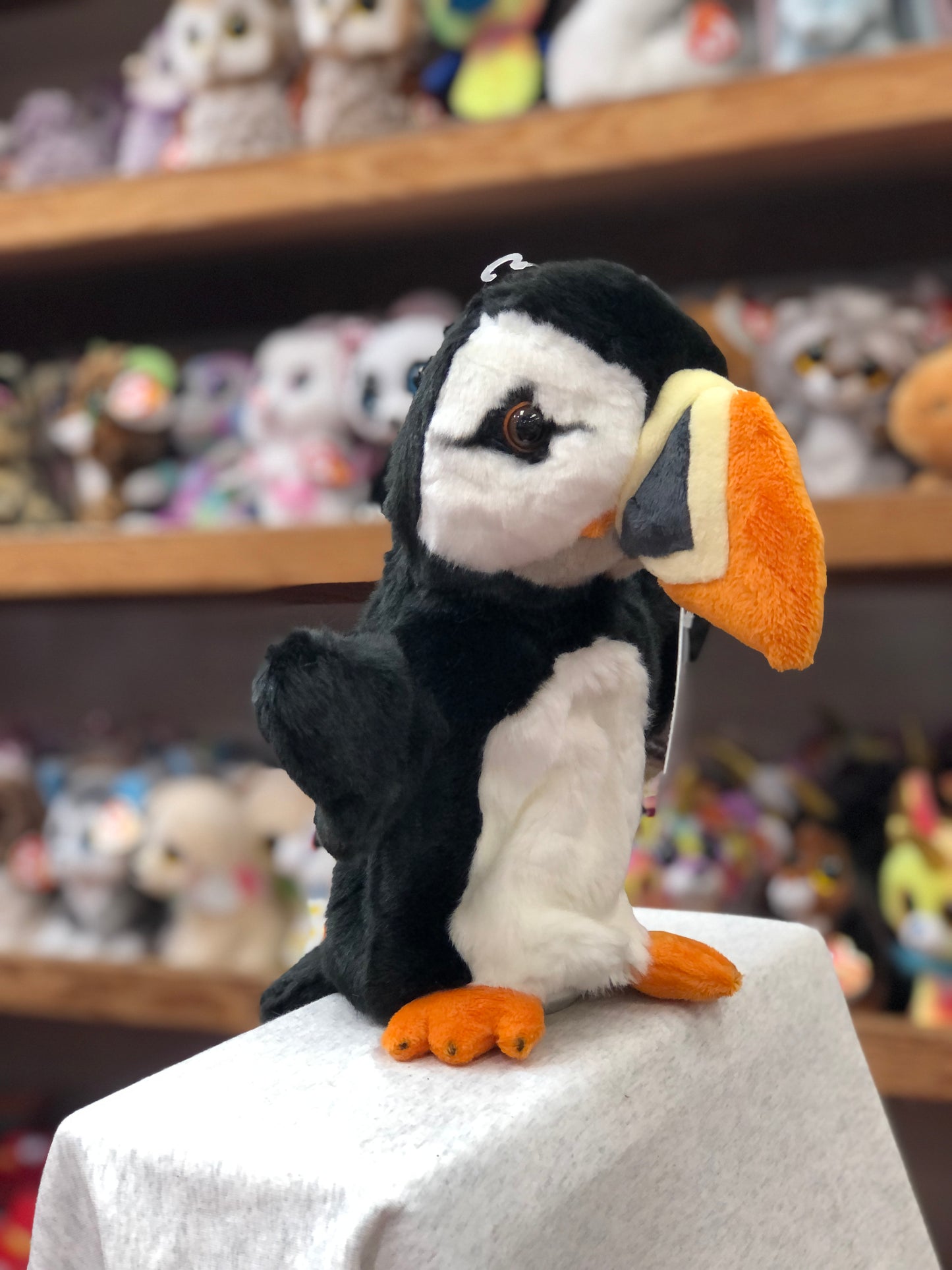 Plush puffin hand puppet from The Puppet Company's CarPets collection, displayed on shelf with other toys