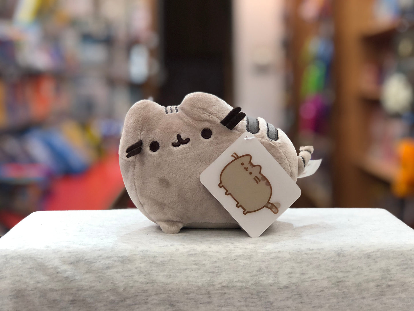 Gund Pusheen plush toy, 6-inch gray cat with cute face, displayed on counter with product tag