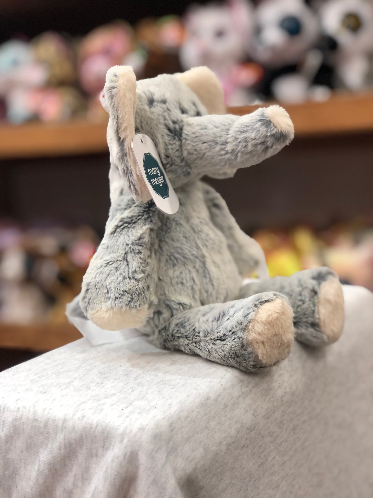 Soft gray Mary Meyer elephant plush toy sitting on display, part of Marshmallow Zoo collection, with tag visible