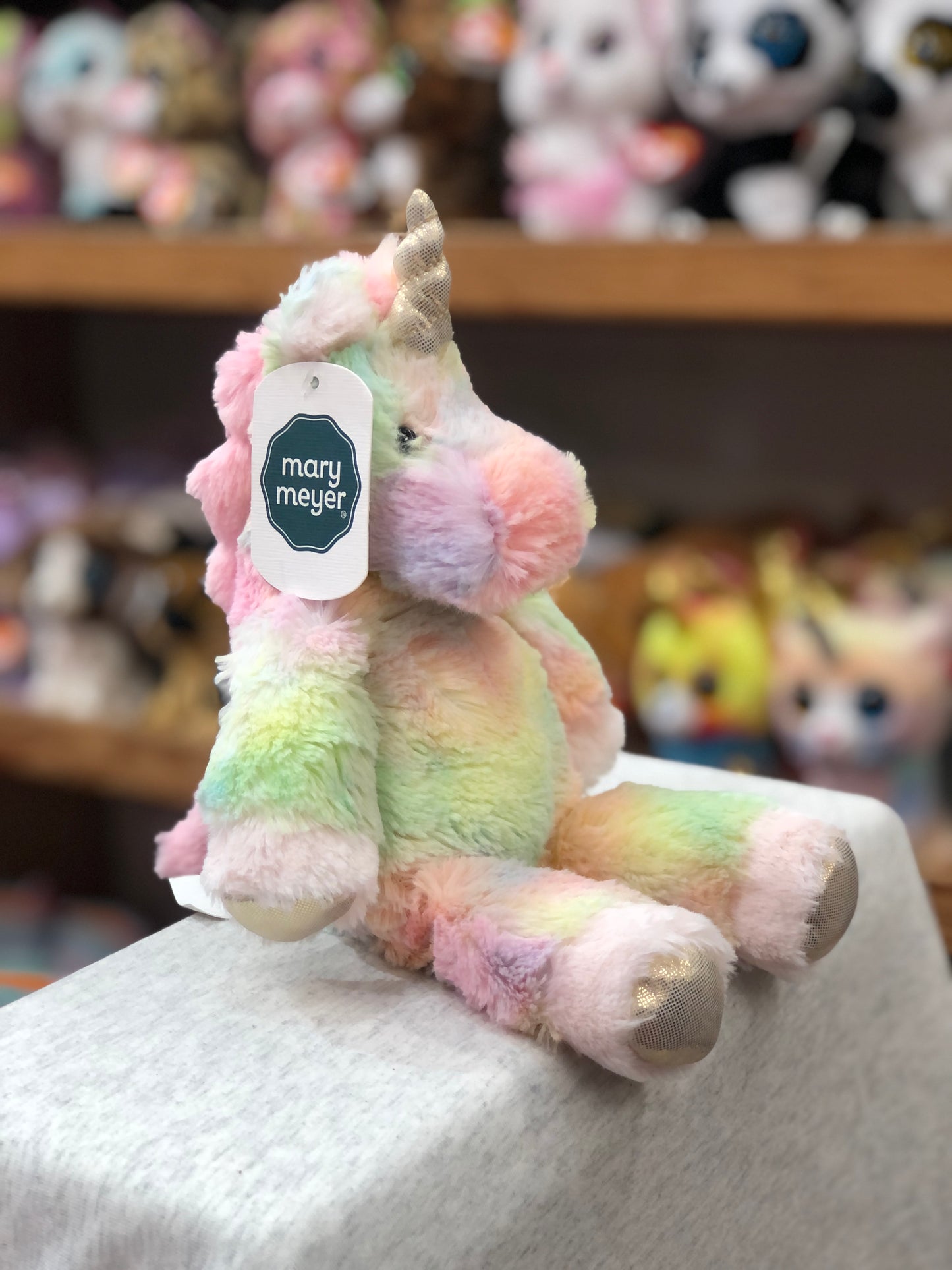 Soft pastel Mary Meyer unicorn plush toy from Marshmallow Zoo collection, displayed on shelf with other stuffed animals