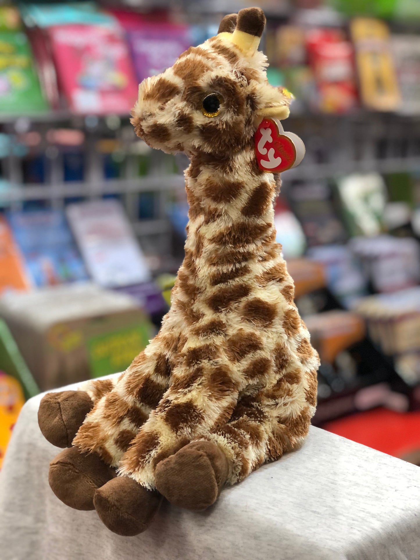 Ty Beanie Baby Gavin the giraffe plush toy with brown spots, long neck, and red heart-shaped tag, sitting on display