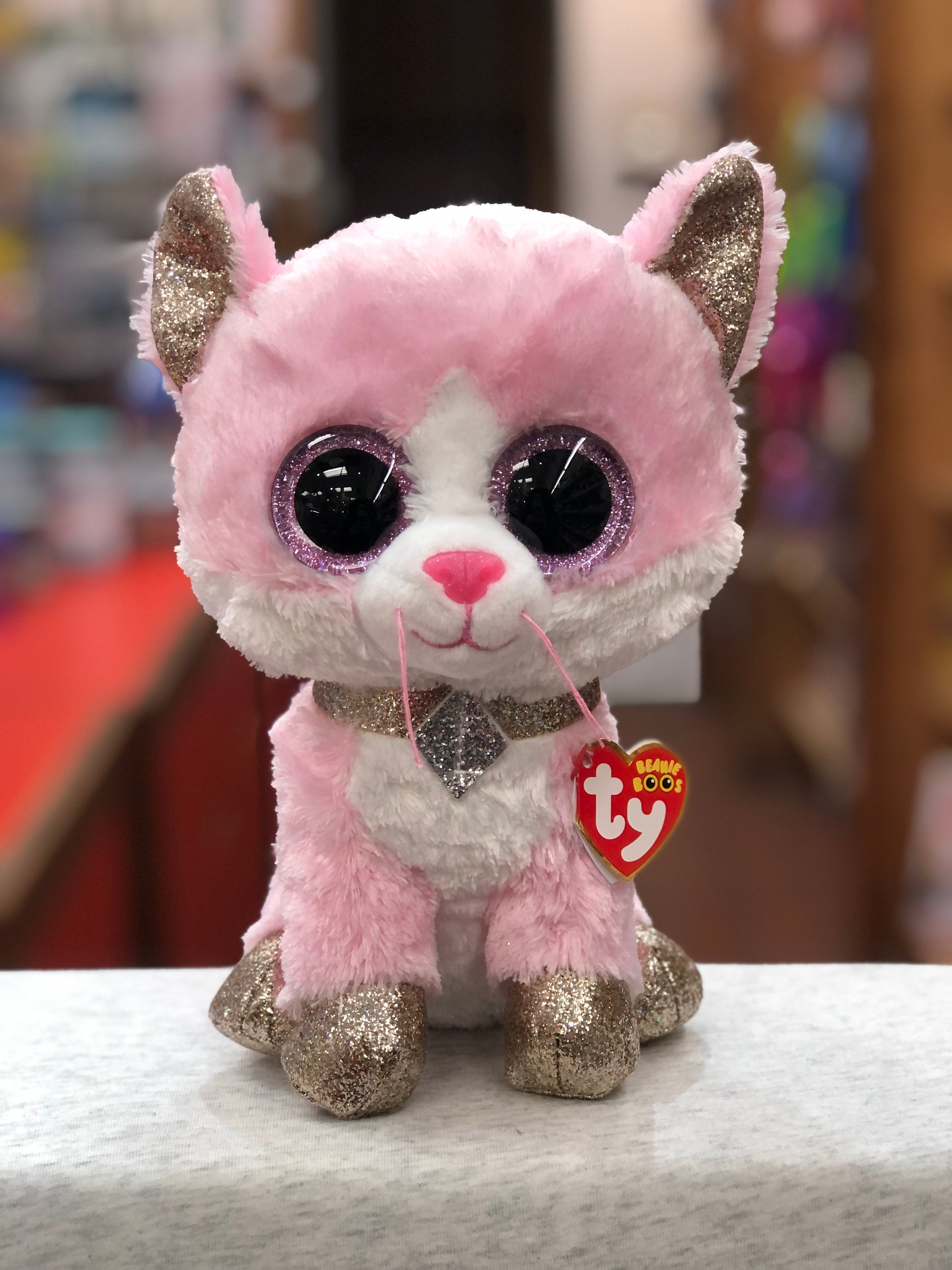 Ty Beanie Boo Fiona pink cat plush with glittery ears, feet, and sparkly necklace, featuring large purple eyes and Ty tag