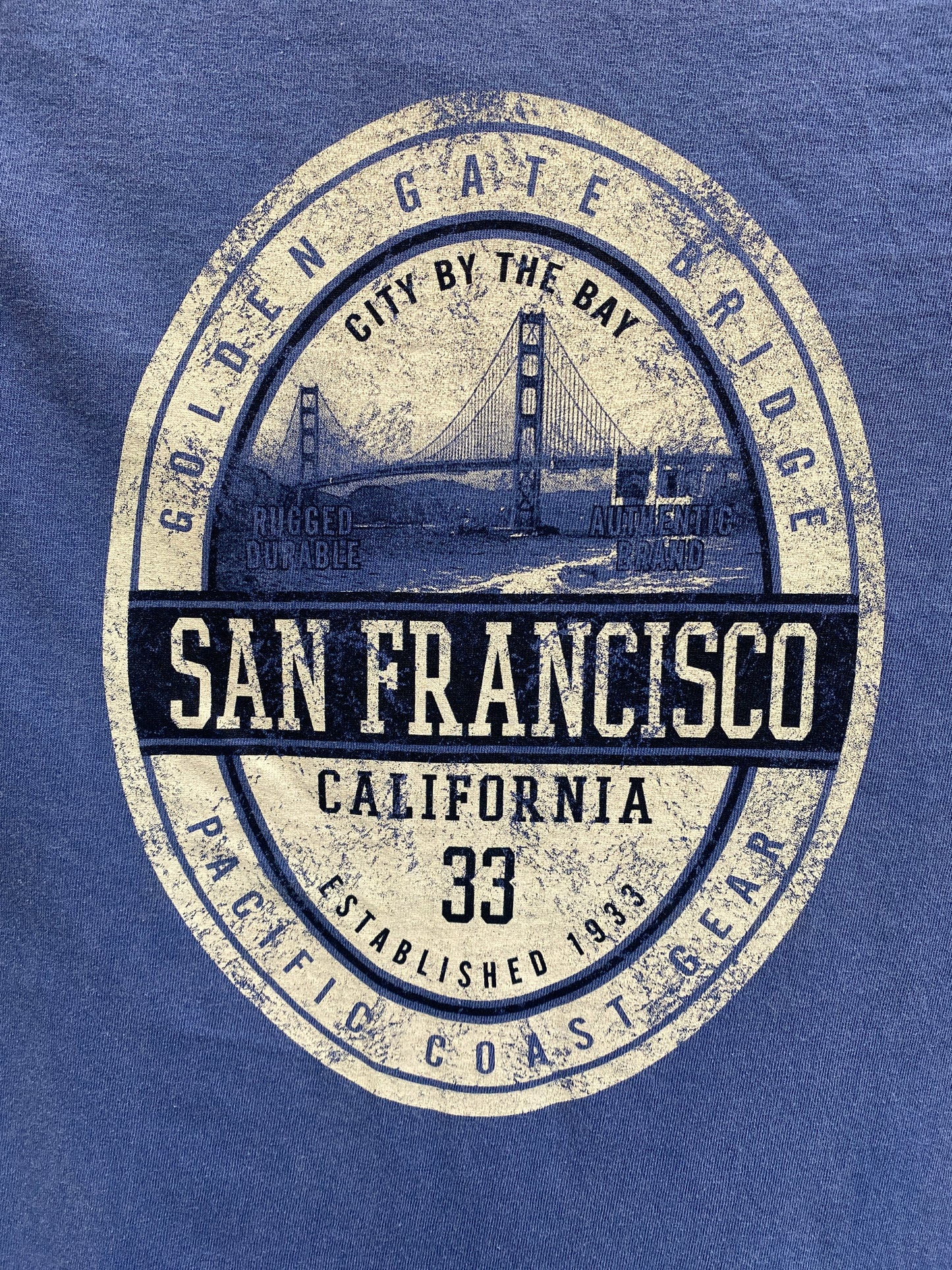 Distressed San Francisco t-shirt design featuring Golden Gate Bridge and vintage-style emblem on blue cotton fabric