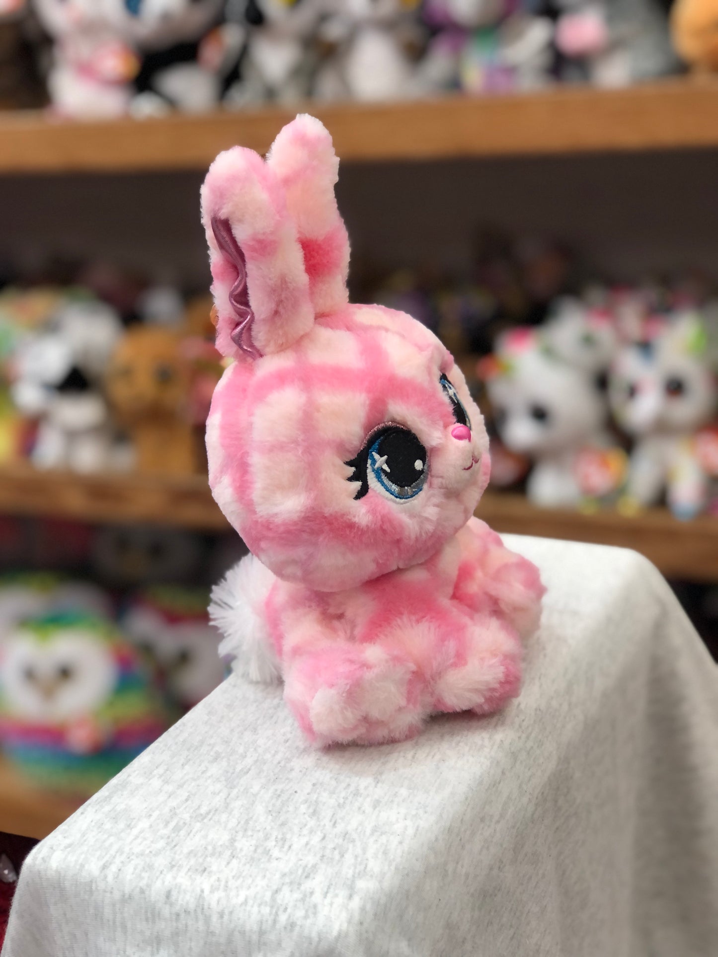 Pink plaid Gund P.Lushes Trixie Karrats plush bunny with blue eyes and purple-accented ears, sitting on display among other toys