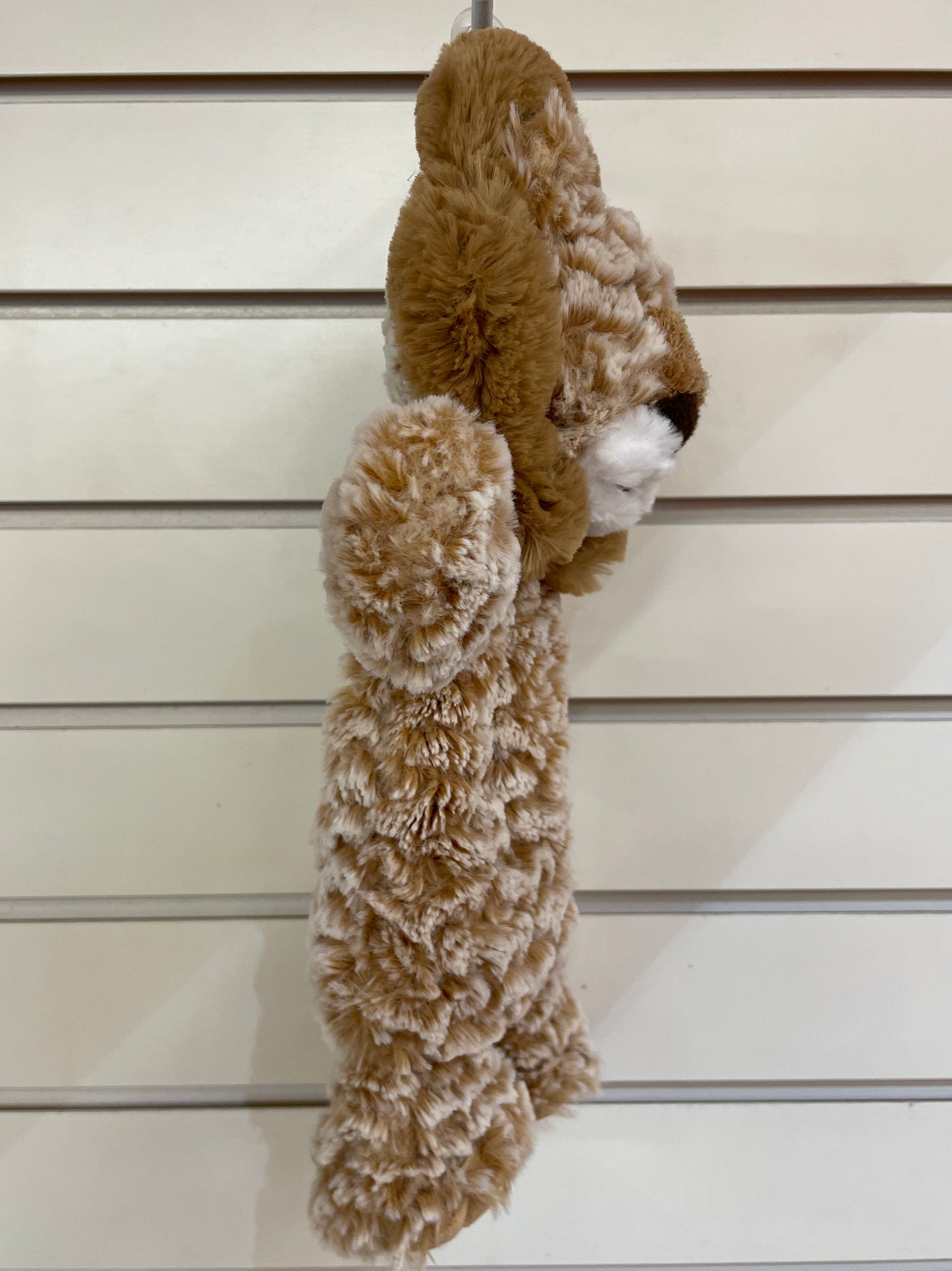Soft tan lion lovey plush toy with embroidered face, hanging on display, showing textured body and understuffed blanket-like design