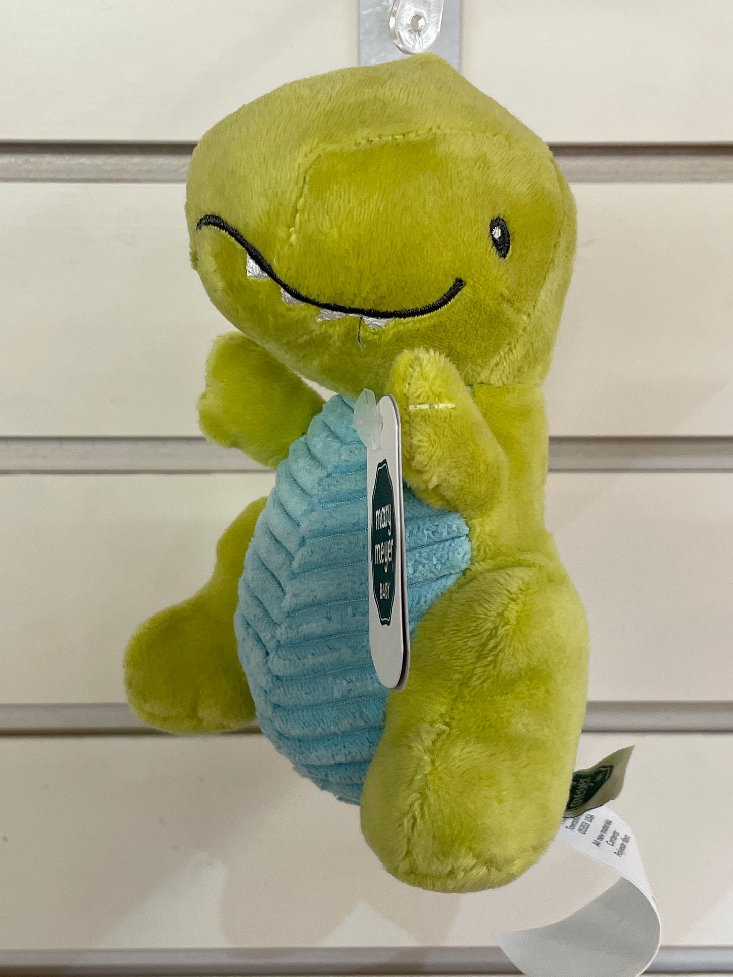 Cute green dinosaur baby rattle with blue belly, embroidered smiling face, and soft plush texture for easy grasping
