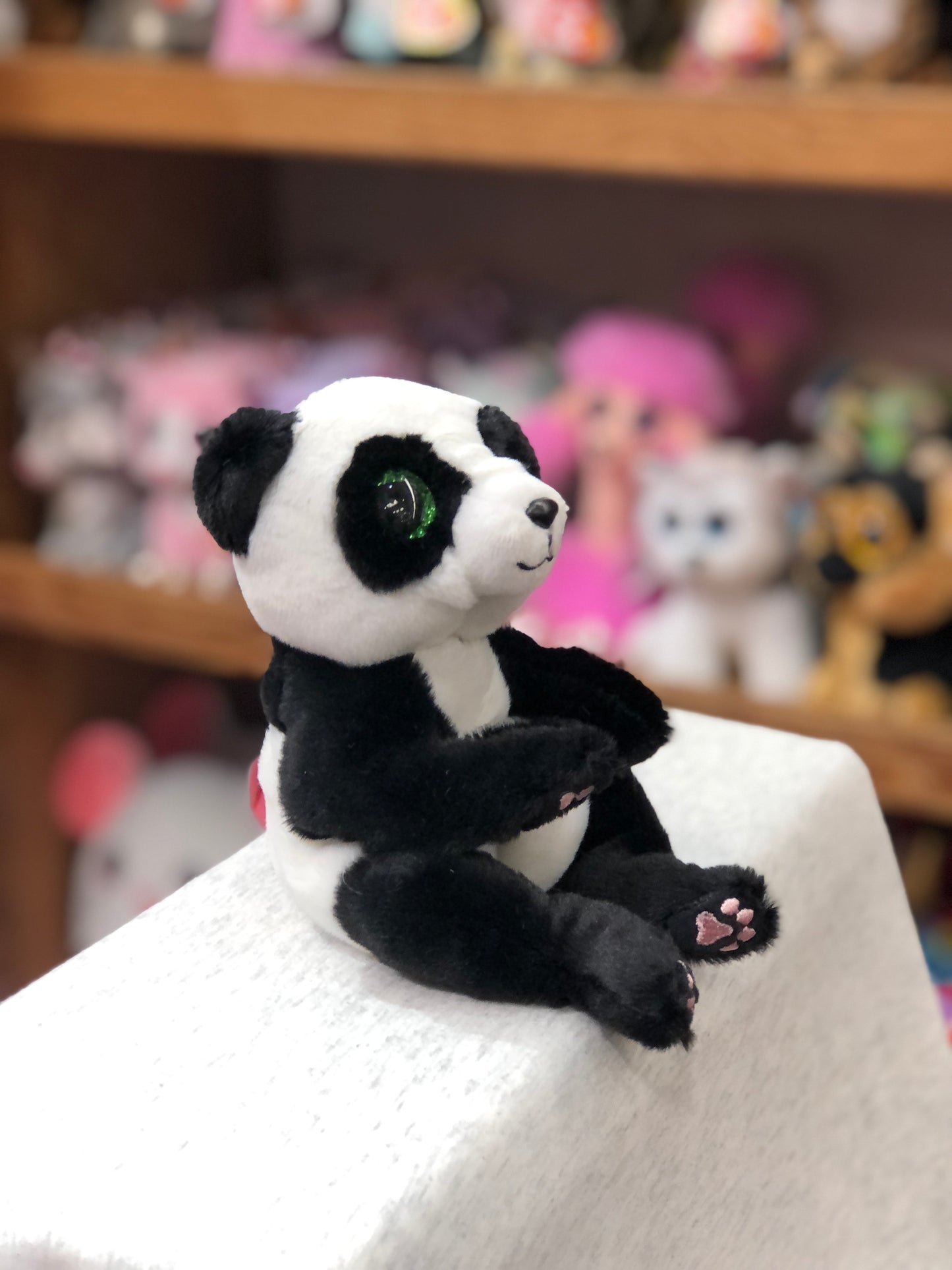 Ty Beanie Belly Ying the Panda plush toy with big green eyes sitting on display, surrounded by other stuffed animals