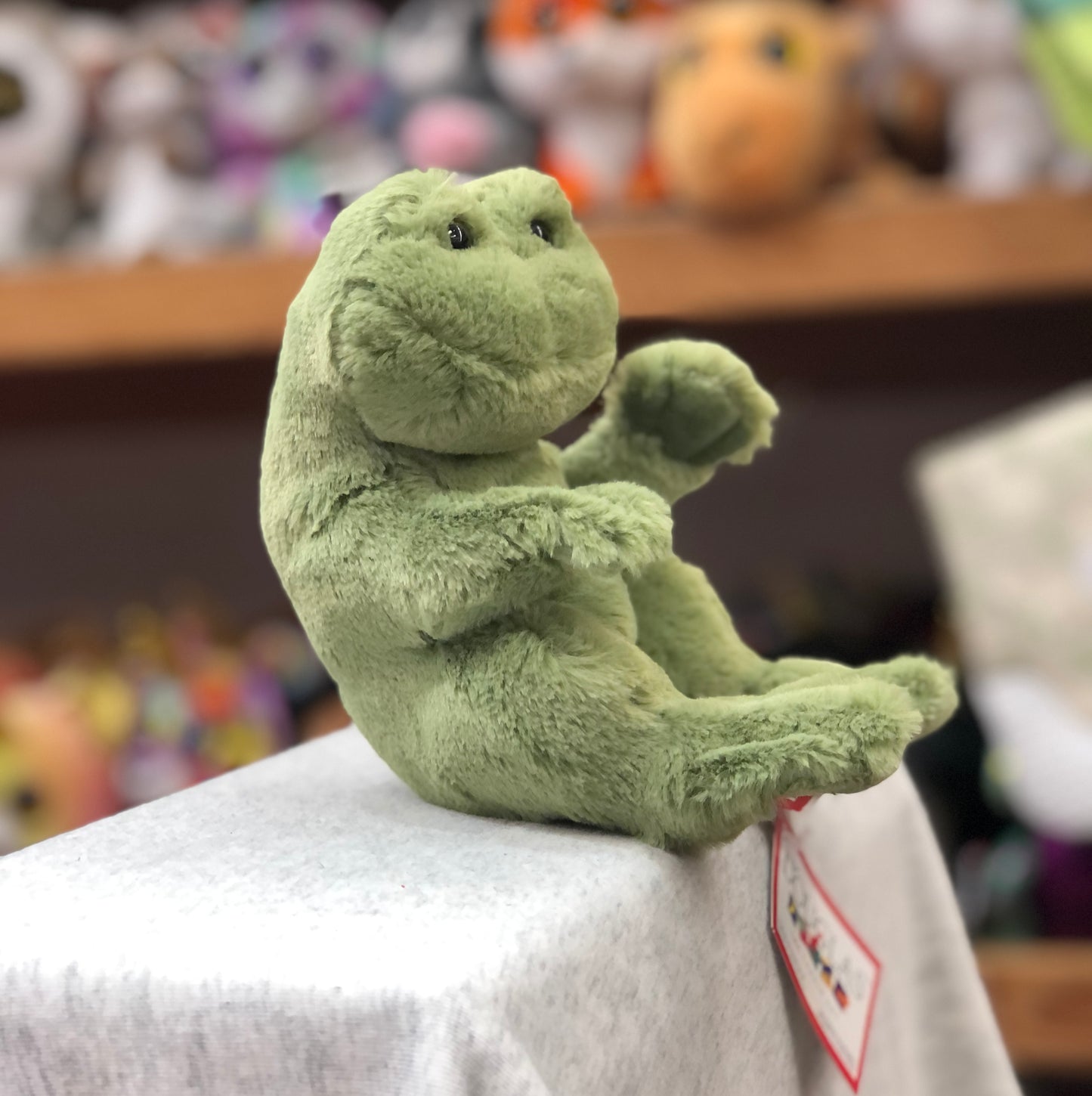 Adorable green Douglas Lil' Baby frog plush toy sitting upright with outstretched arms, soft fuzzy texture, and bright eyes