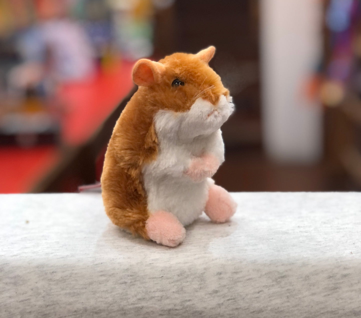 Adorable Douglas Brushy Hamster plush toy with golden-brown fur, white belly, and pink paws sitting upright on a white surface