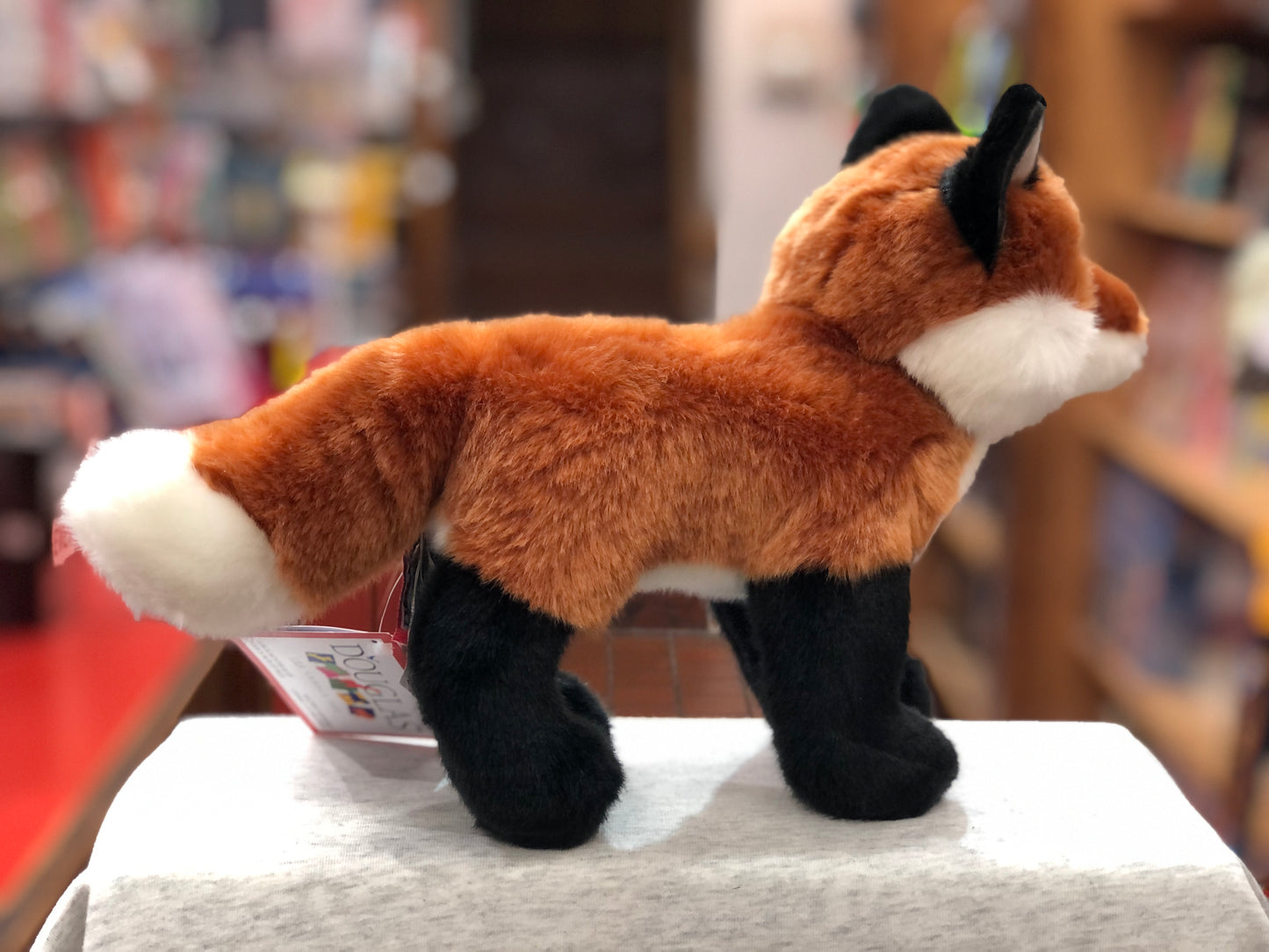 Lifelike Douglas red fox plush toy with russet coat, white-tipped tail, and black legs on display in store
