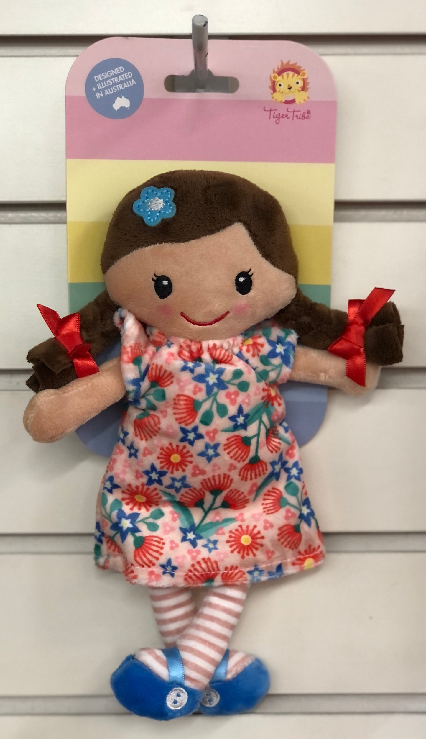 Mini rag doll Matilda in floral dress, pigtails with red ribbons, striped socks, and blue shoes, displayed on colorful packaging