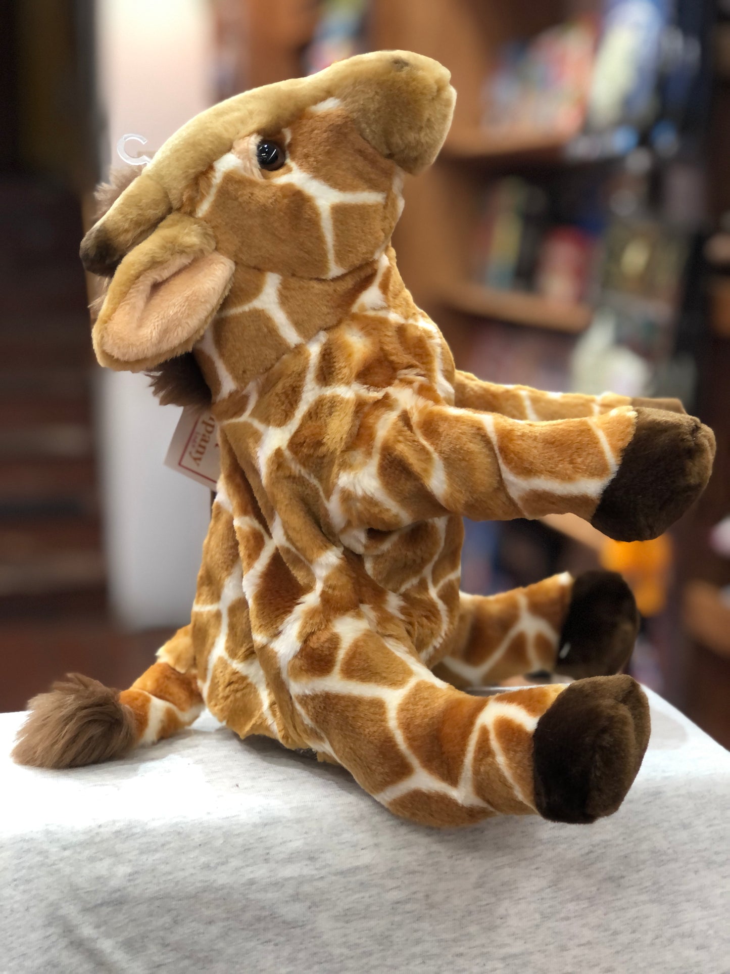 Cuddly full-bodied giraffe puppet with realistic pattern, sitting on white surface, perfect for playtime and storytelling