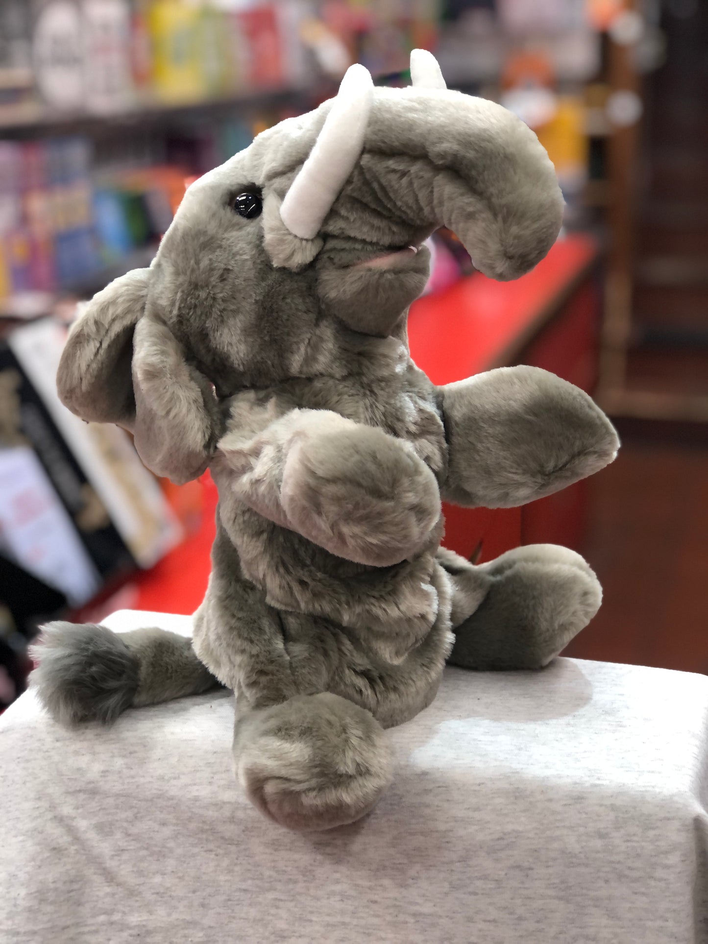 Cuddly gray elephant full-bodied puppet sitting on display, featuring soft plush texture and movable trunk for interactive play