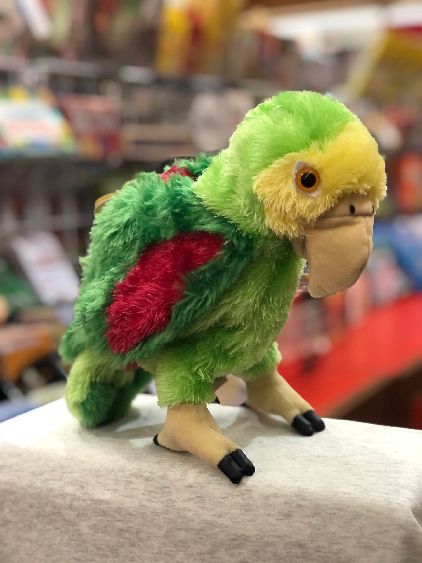 Colorful Folkmanis Amazon Parrot puppet with vibrant green, yellow, and red plush feathers, large beak, and realistic feet