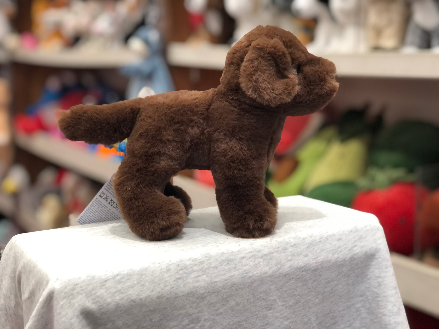 Soft, realistic 7" Douglas Chocolate Lab plush toy displayed on white surface, showcasing cuddly brown fur and lifelike features