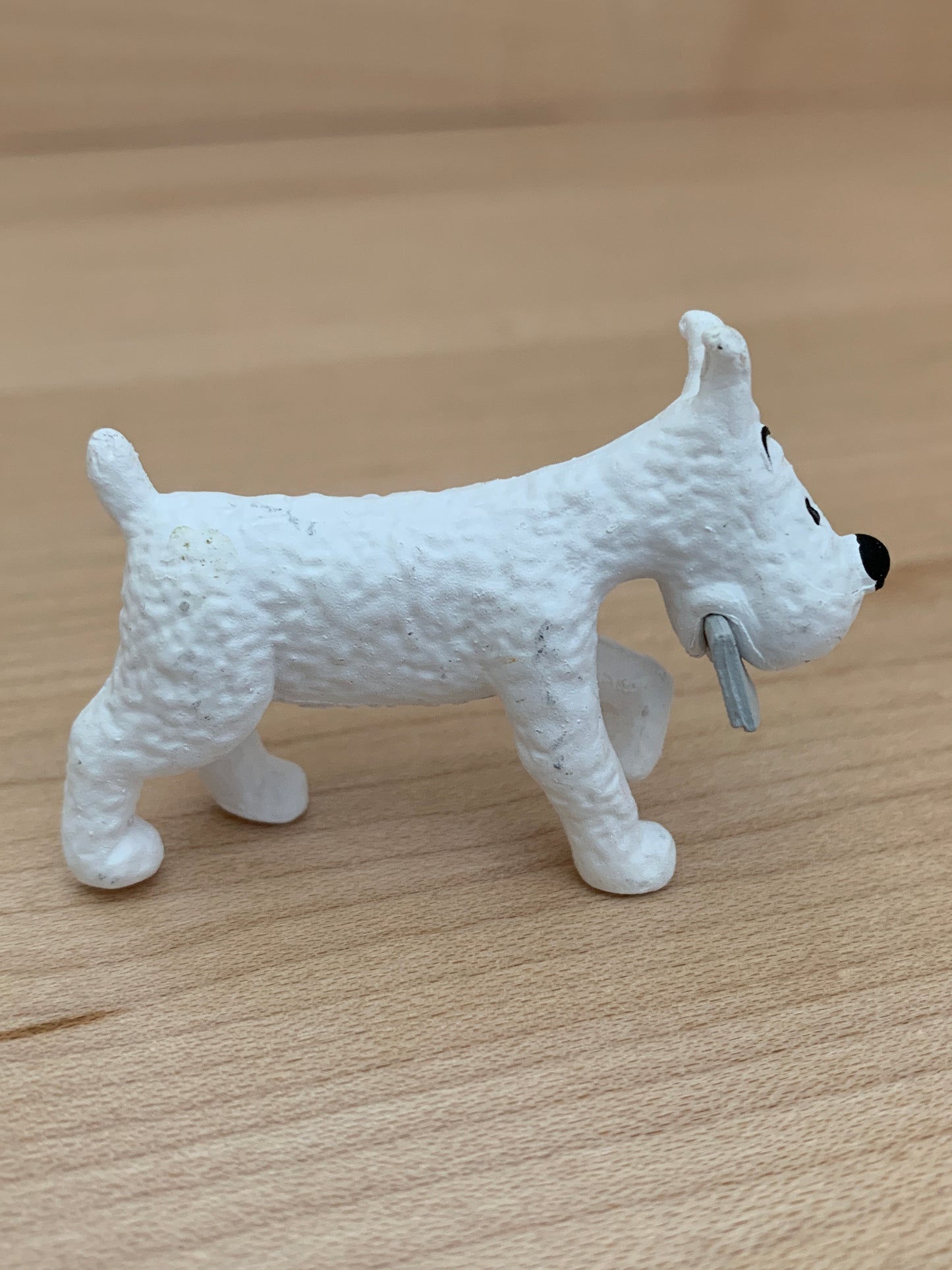 Snowy the dog mini figure from Tintin in Tibet, white PVC, 5.4cm long, carrying message in mouth on wooden surface