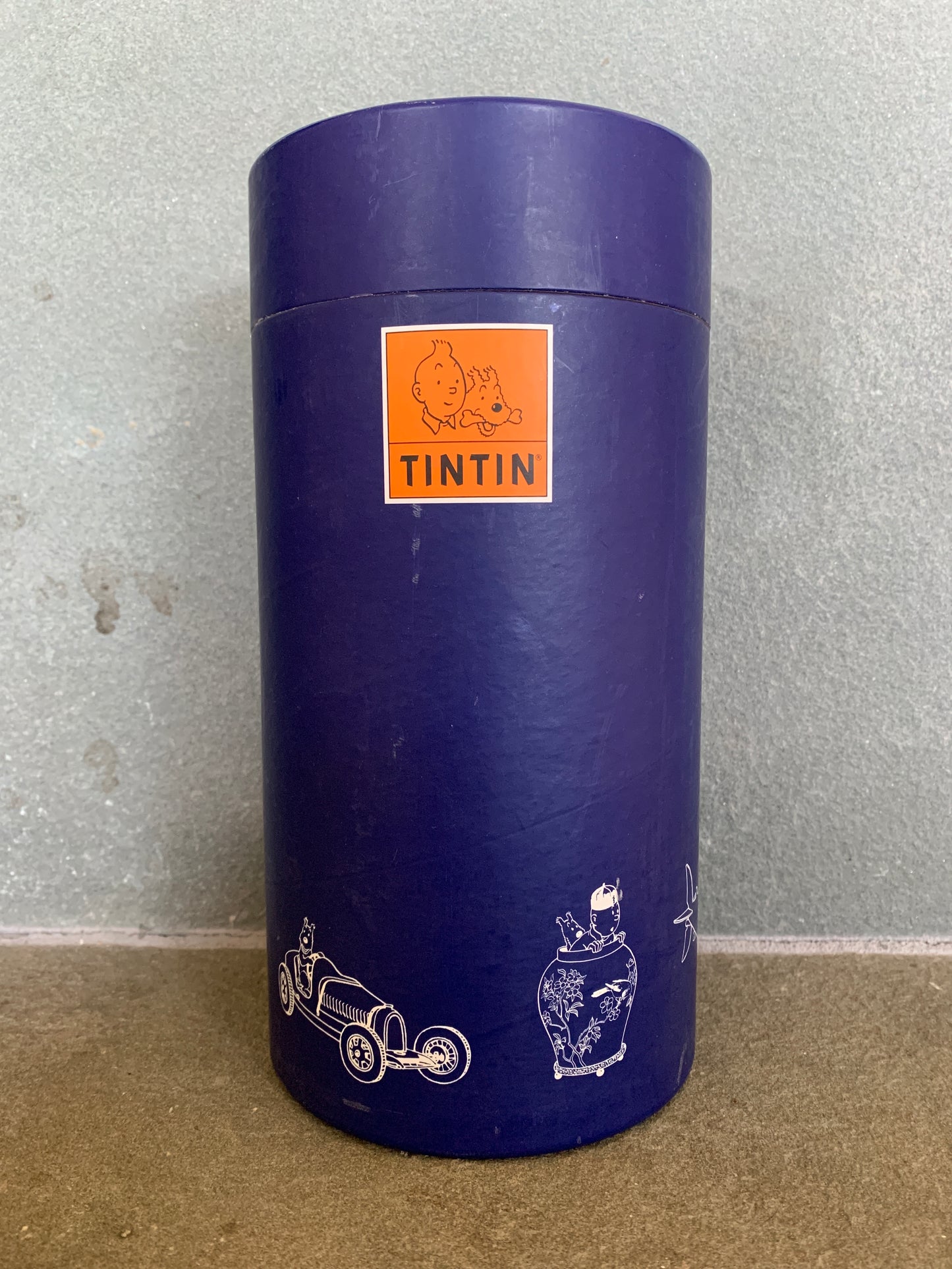 Tintin 17cm Moon Rocket box, purple cylinder with orange logo and decorative illustrations, collectible 2012 Moulinsart item