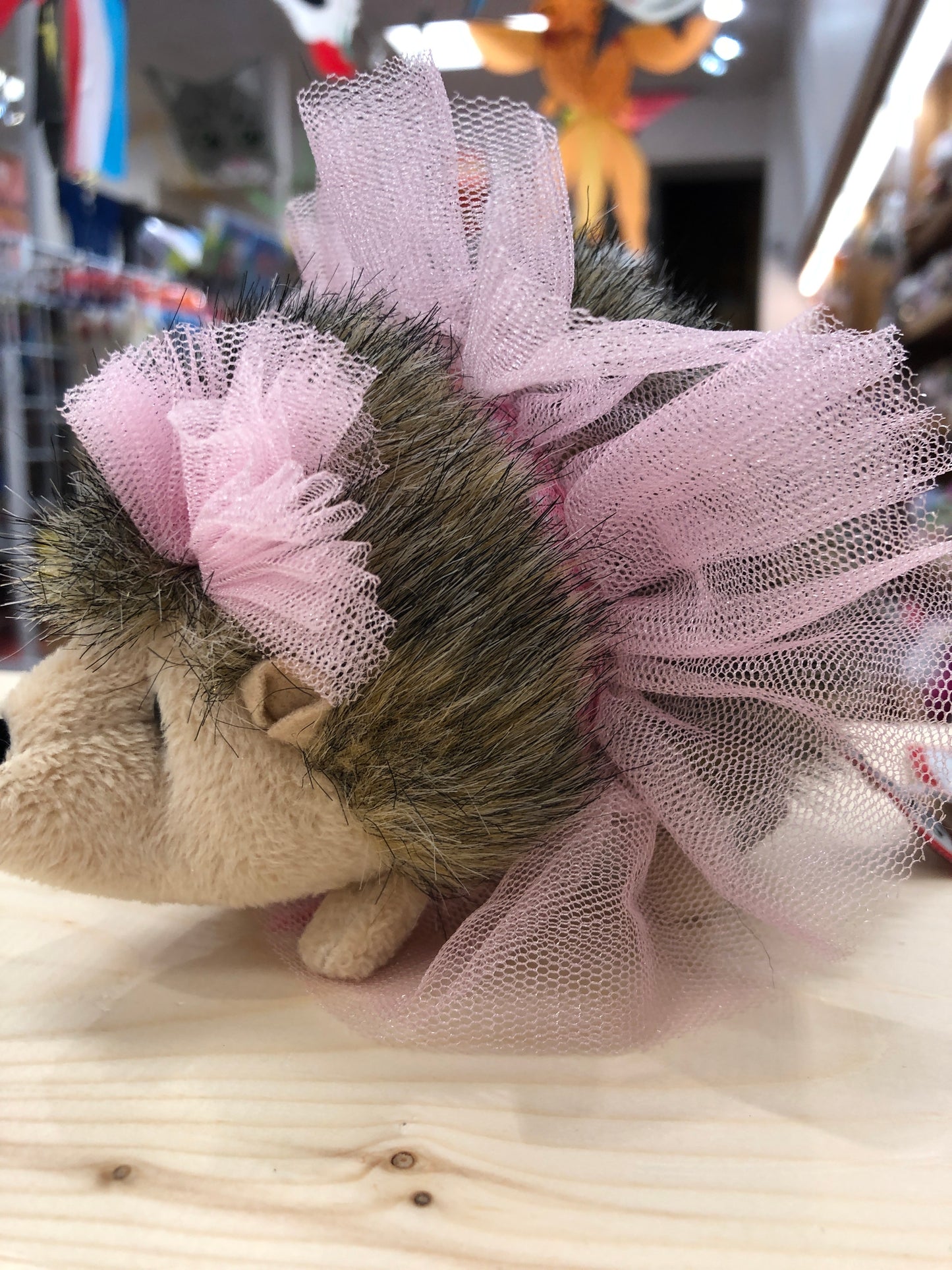 Cute plush hedgehog toy wearing pink tutu, close-up view of spiky back and tulle skirt in toy store