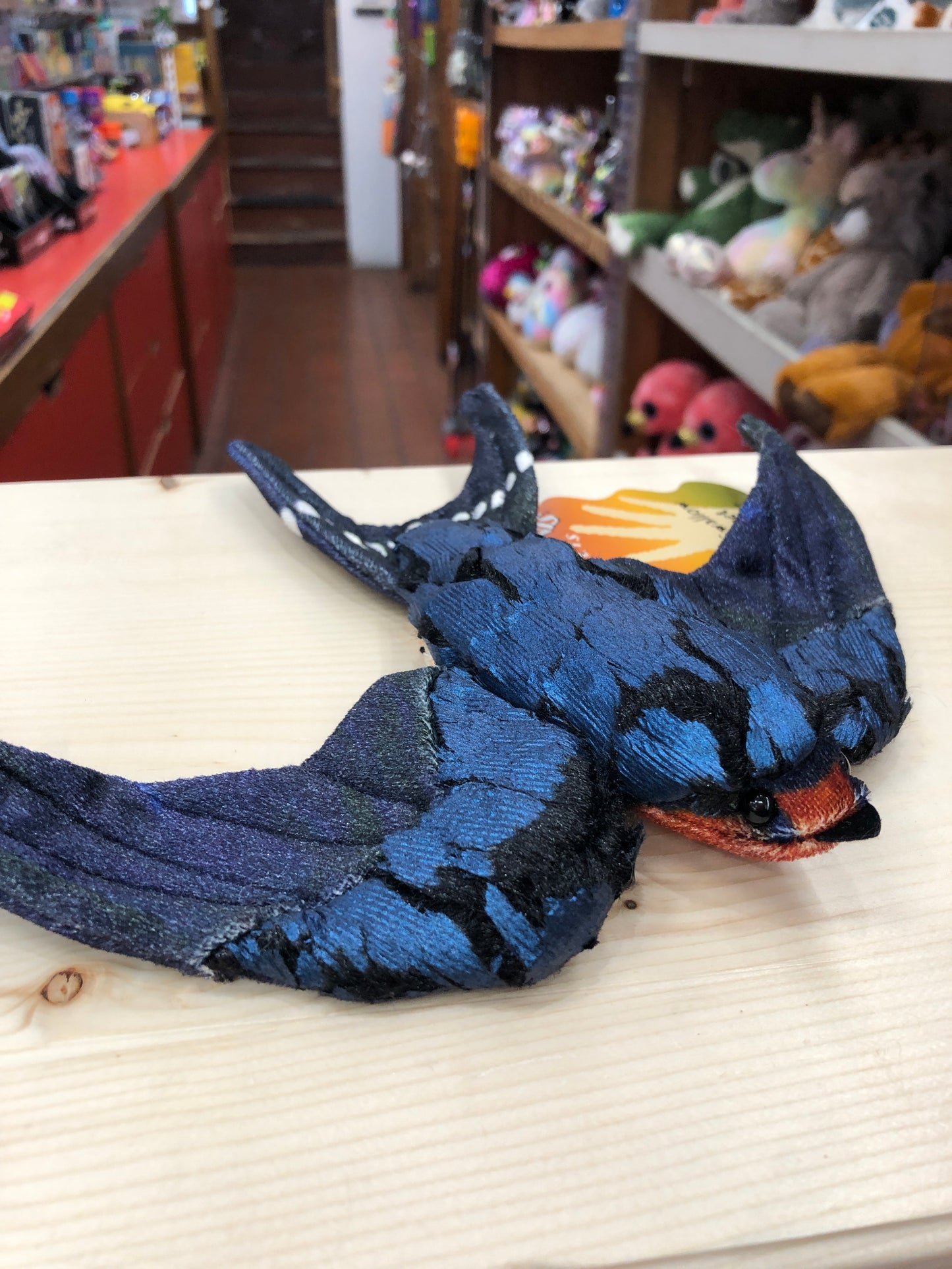 Folkmanis Barn Swallow finger puppet with blue-black feathers and forked tail on display in toy store, showcasing realistic design