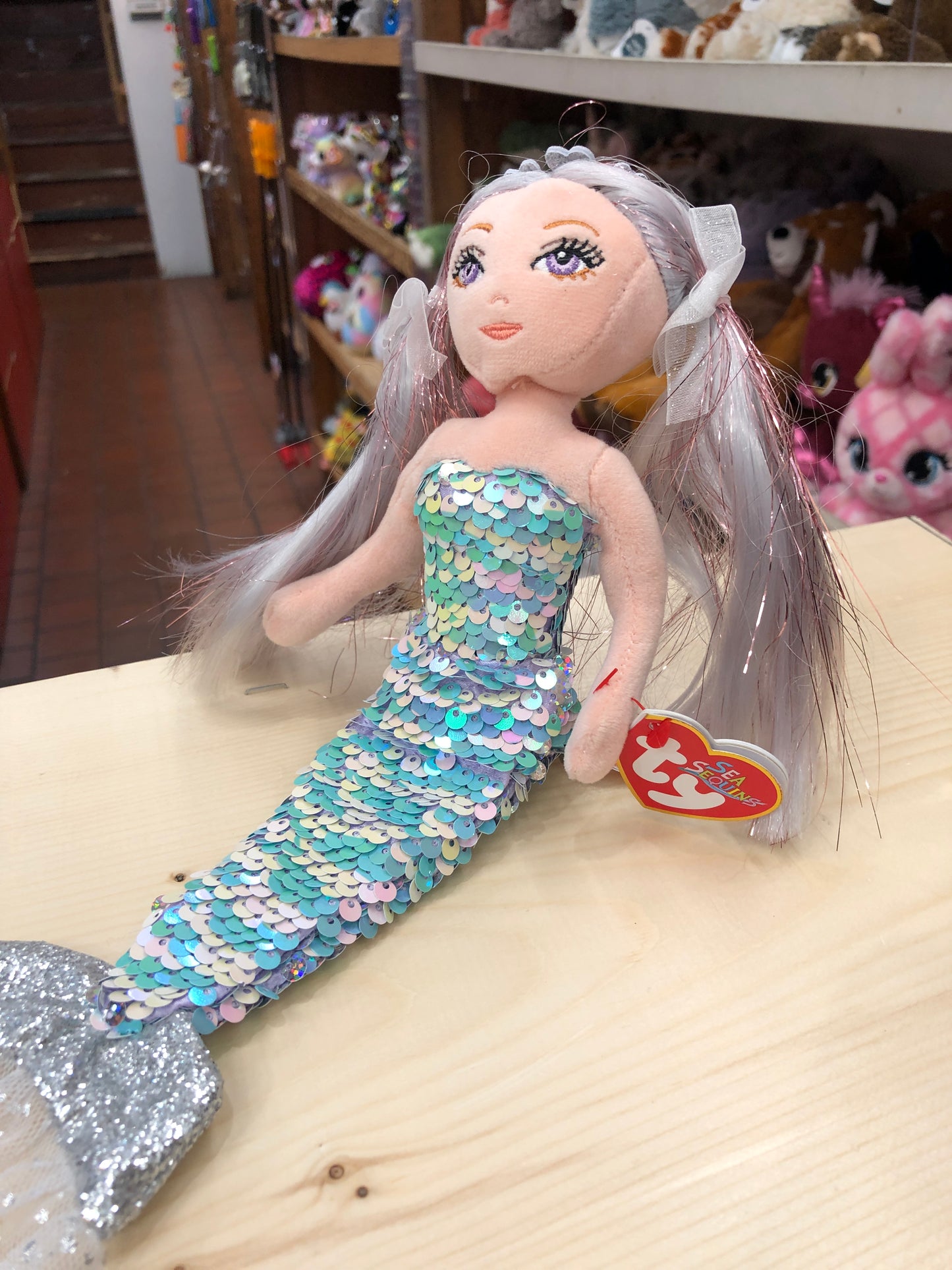 Ty Sea Sequins Athena mermaid plush toy with iridescent sequin tail, silver hair, and Ty heart tag on display shelf