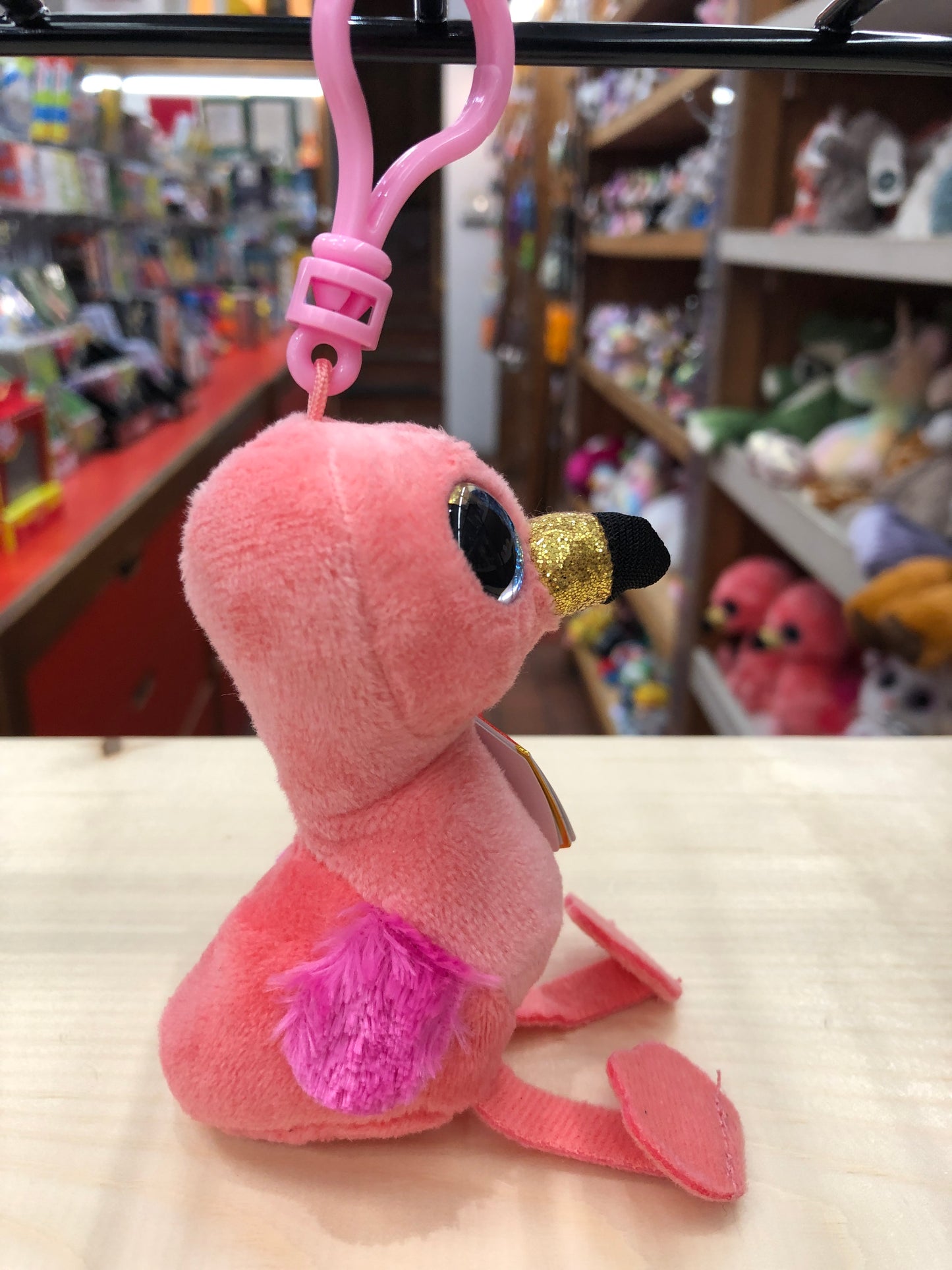 Ty Beanie Boo Gilda pink flamingo plush clip with sparkly eyes and gold beak, displayed in toy store