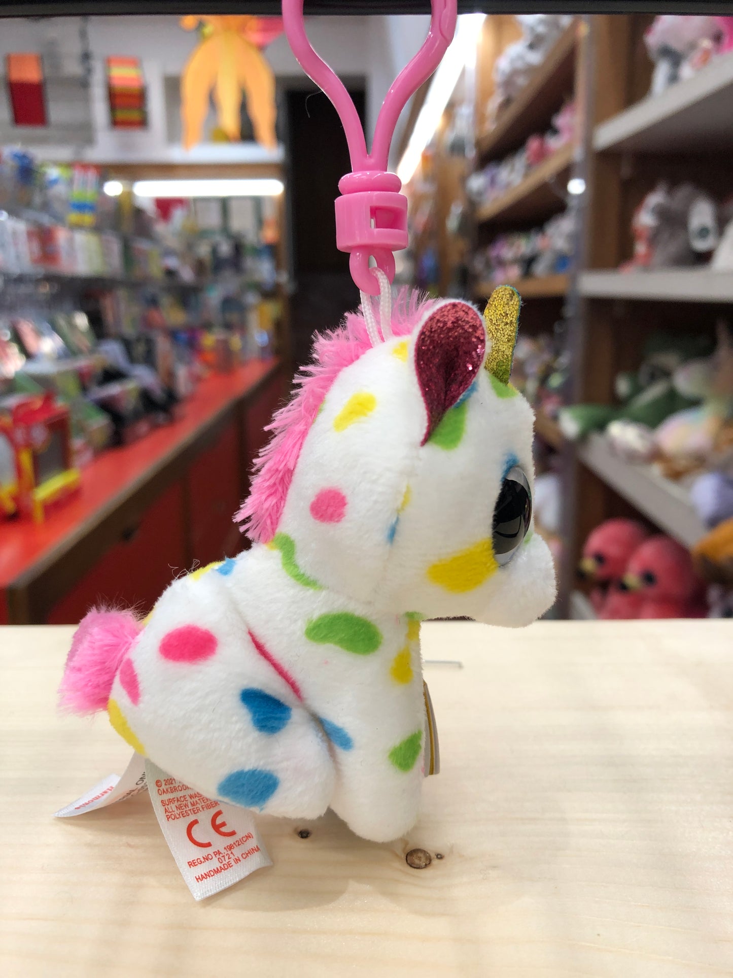 Colorful Ty Beanie Boo Harmonie unicorn plush clip with sparkly horn and multicolored spots in toy store display