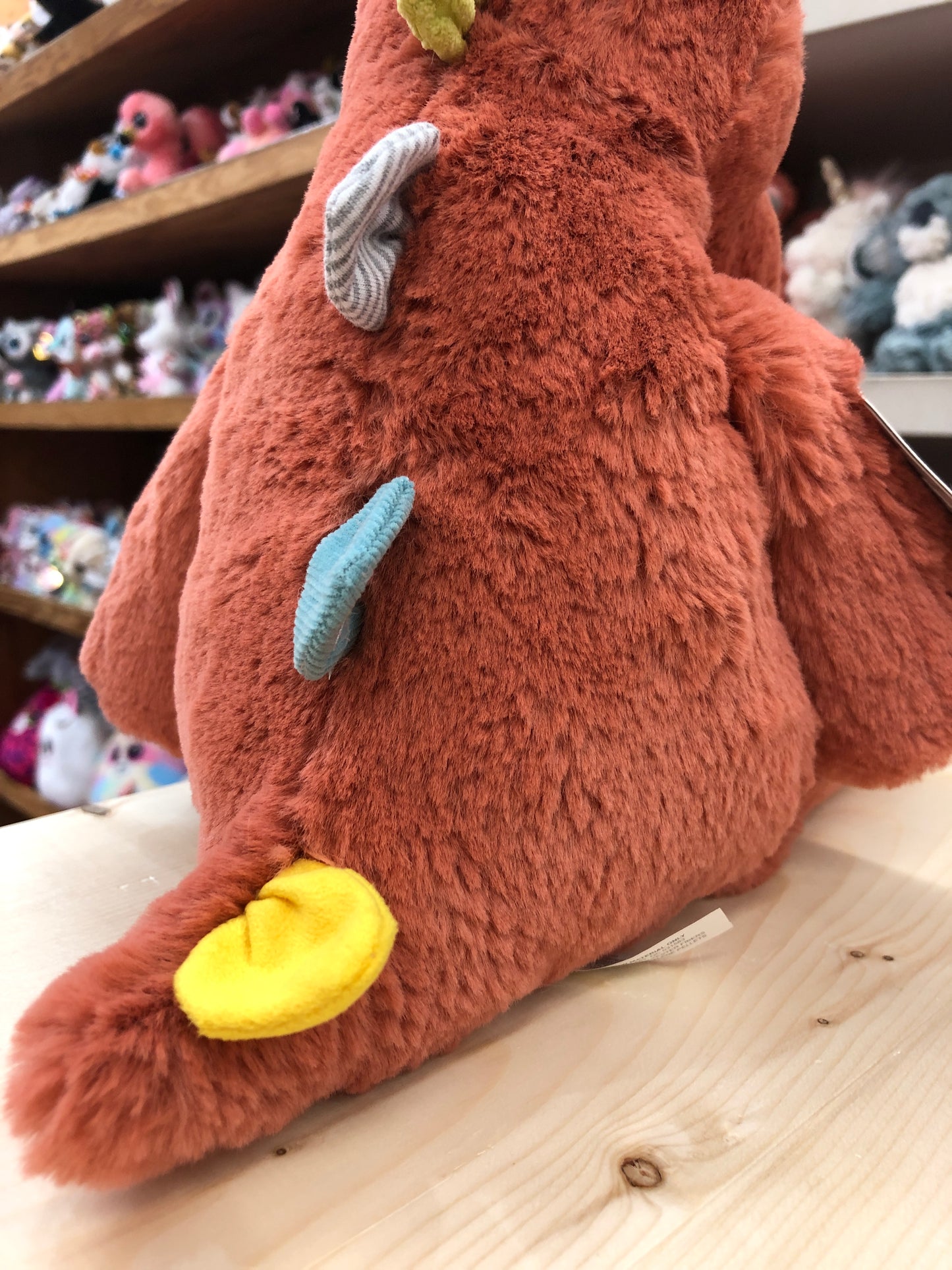 Soft, plush Marshmallow Stegosaurus toy with colorful spikes, showcasing its fluffy texture and cuddly design on store shelf