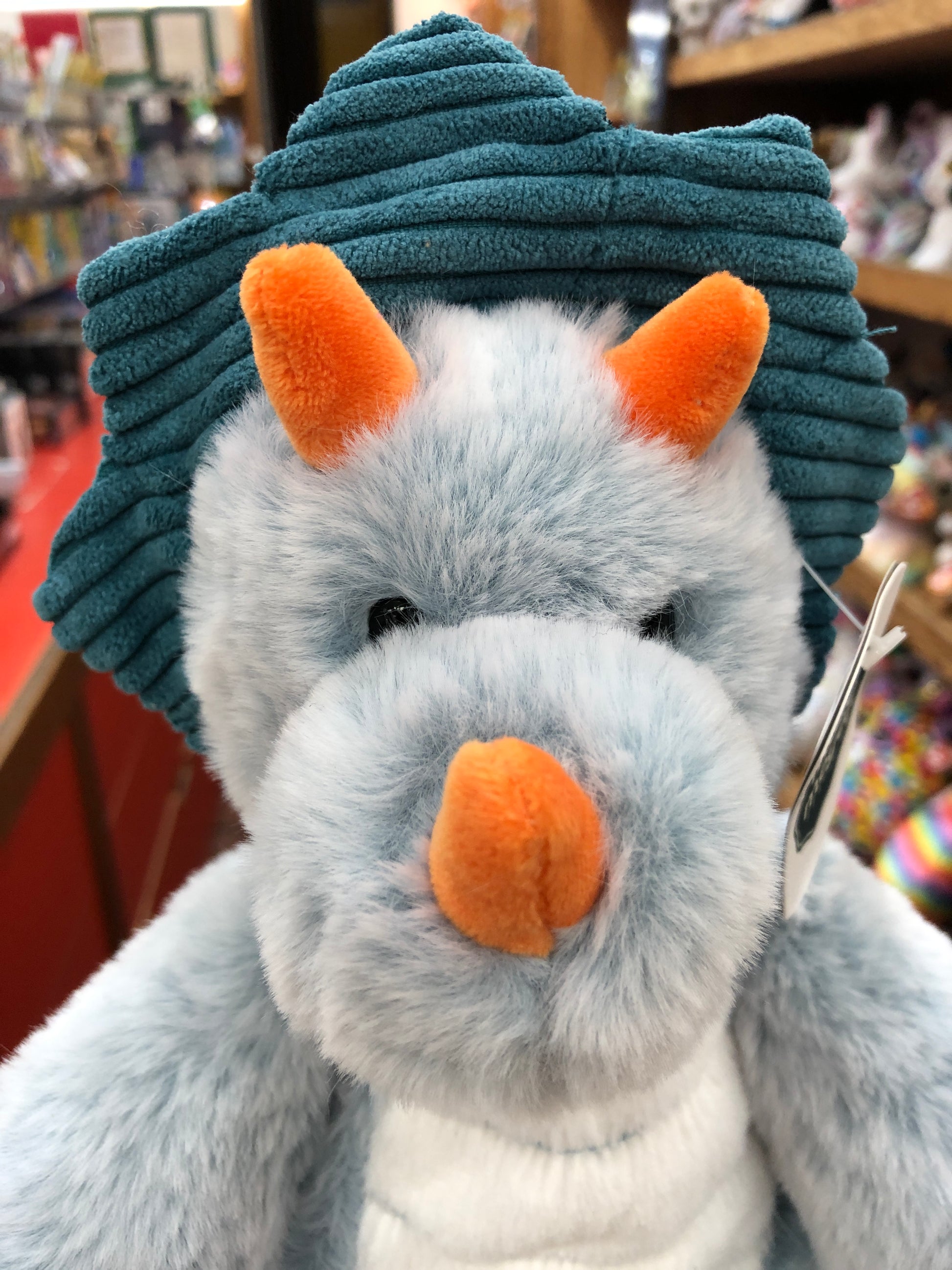 Soft plush triceratops toy with teal ridged head, gray fur, and orange horn and ears from Mary Meyer Marshmallow Zoo collection